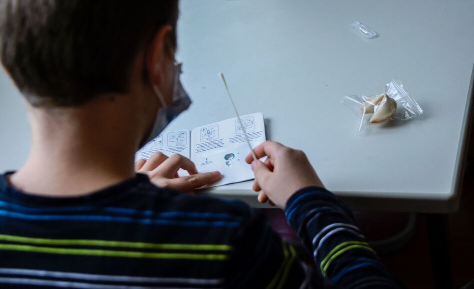 A pupil wearing a face mask reads instructions for a coronavirus rapid test kit at the start of a lesson at an elementary school in Berlin on August 9, 2021. (Tobias Schwarz/AFP via Getty Images)