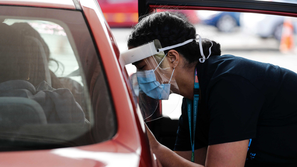 A Health worker administers vaccinations at a pop-up drive-in clinic Monday, Oct. 11, 2021, in Auckland, New Zealand. New Zealand