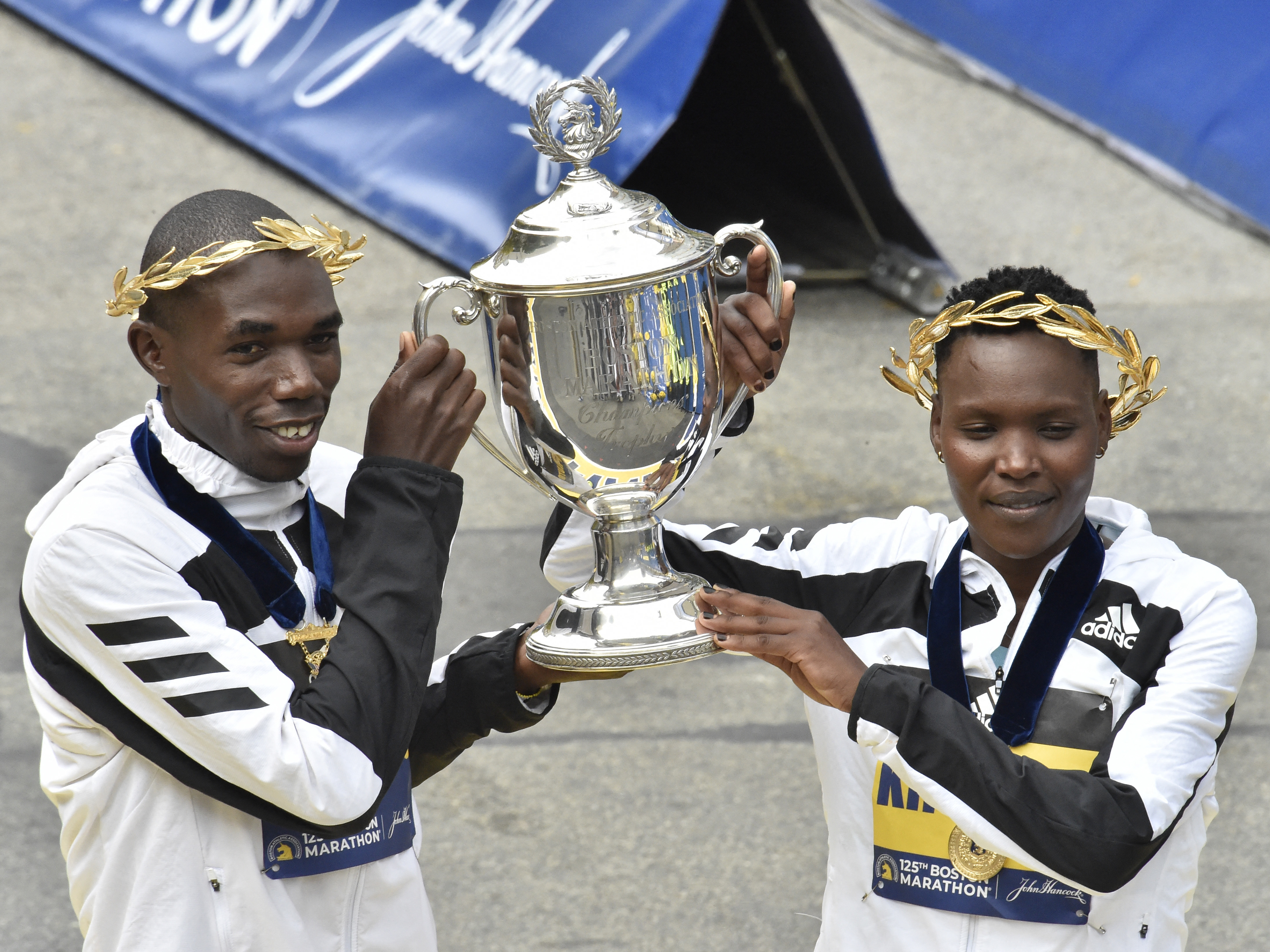 Benson Kipruto (L) and Diana Kipyogei (R) of Kenya hold up the victory trophy after taking first place in the professional men's and women's divisions during the 125th Boston Marathon in Boston, Massachusetts on Monday. The first Boston Marathon since April 2019 strayed from tradition in several ways. (AFP via Getty Images)