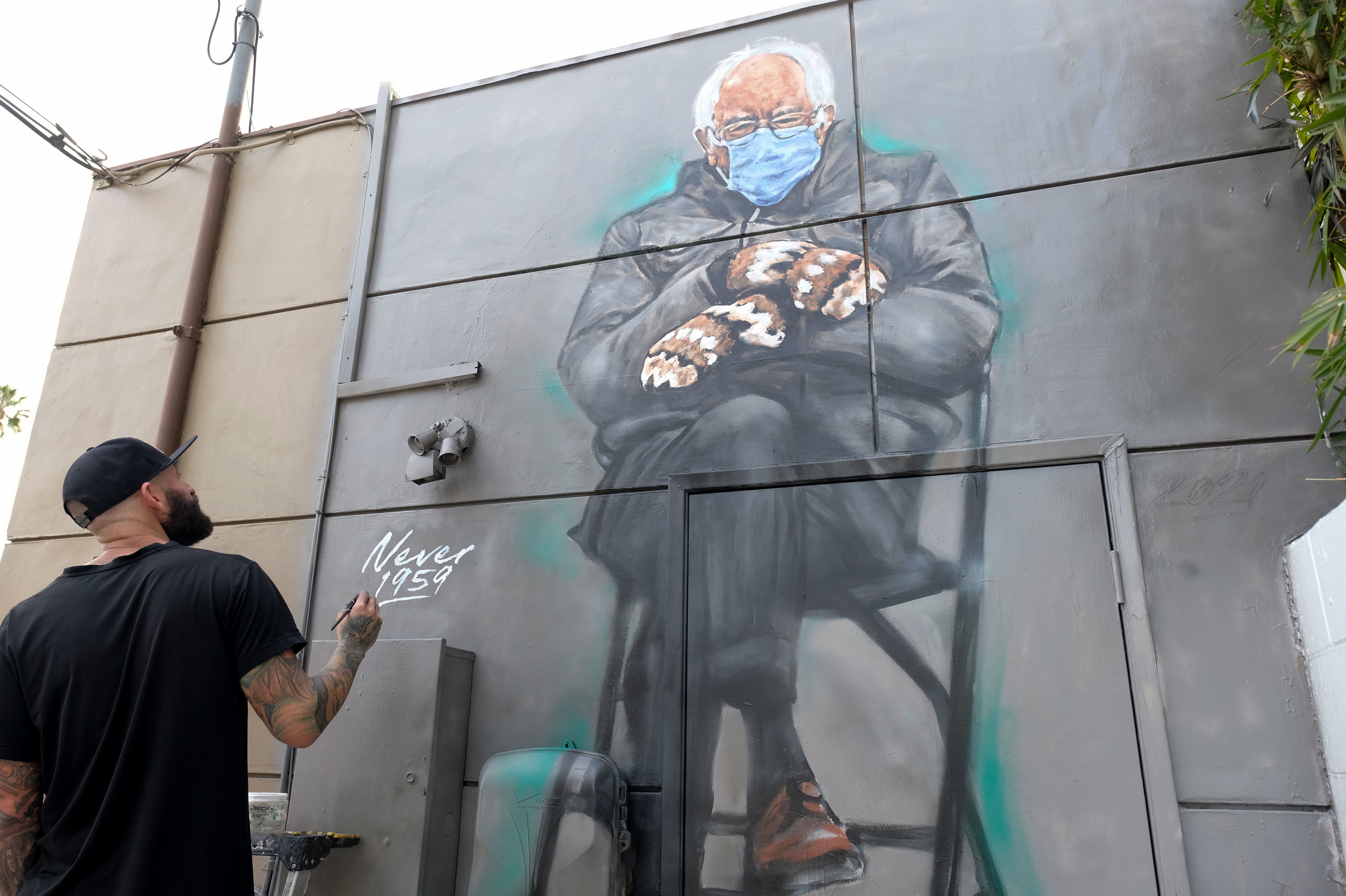 Artist Jonas Never (@never1959) applies finishing touches to his mural of Sen. Bernie Sanders in Culver City, Calif., on Jan. 24. Standing out in a crowd of glamorously dressed guests, Sanders showed up for the presidential inauguration in a heavy winter jacket and patterned mittens — with an AFP photo of the veteran leftist spawning the first viral meme of the Biden era. (AFP via Getty Images)