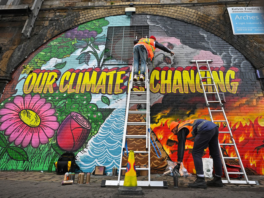 Artists paint a mural on a wall near Scottish Events Centre (SEC) in Glasgow, which is hosting the U.N. climate summit that started on Sunday. (Getty Images)