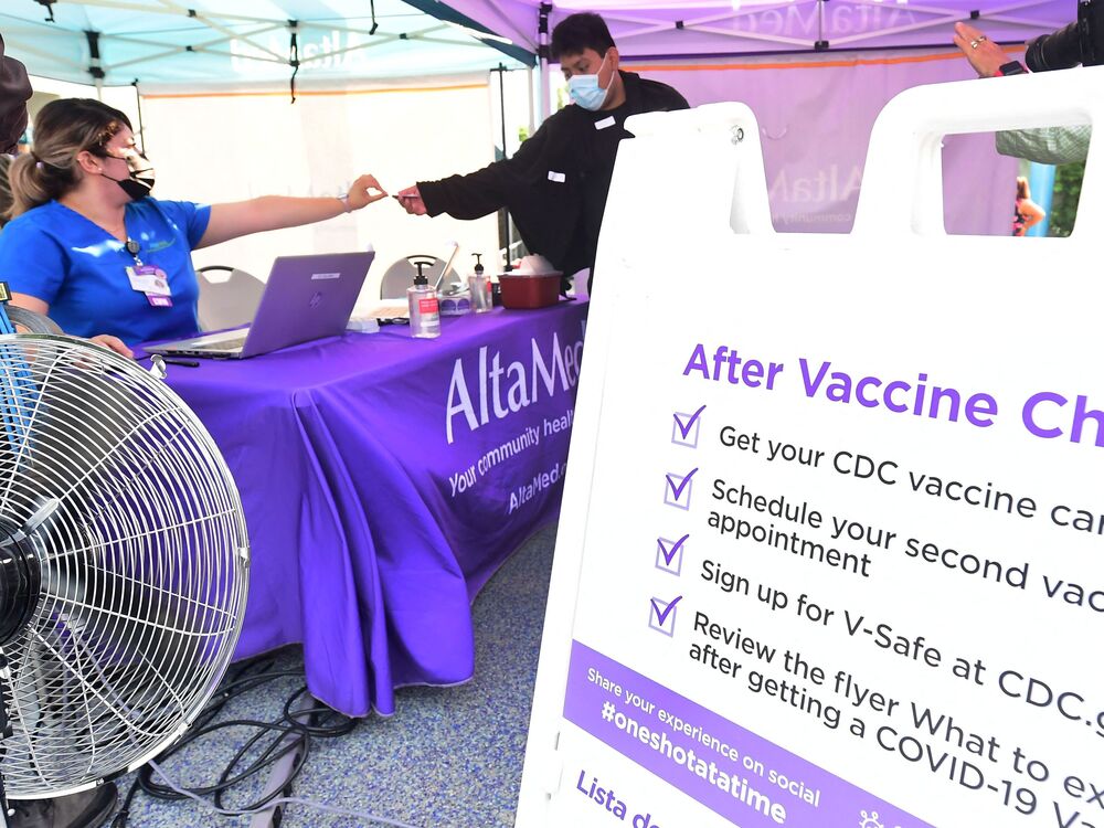 A nurse from AltaMed Health Services hands out the vaccine card to people after receiving their Covid-19 vaccine in Los Angeles, California on August 17, 2021. (AFP via Getty Images)