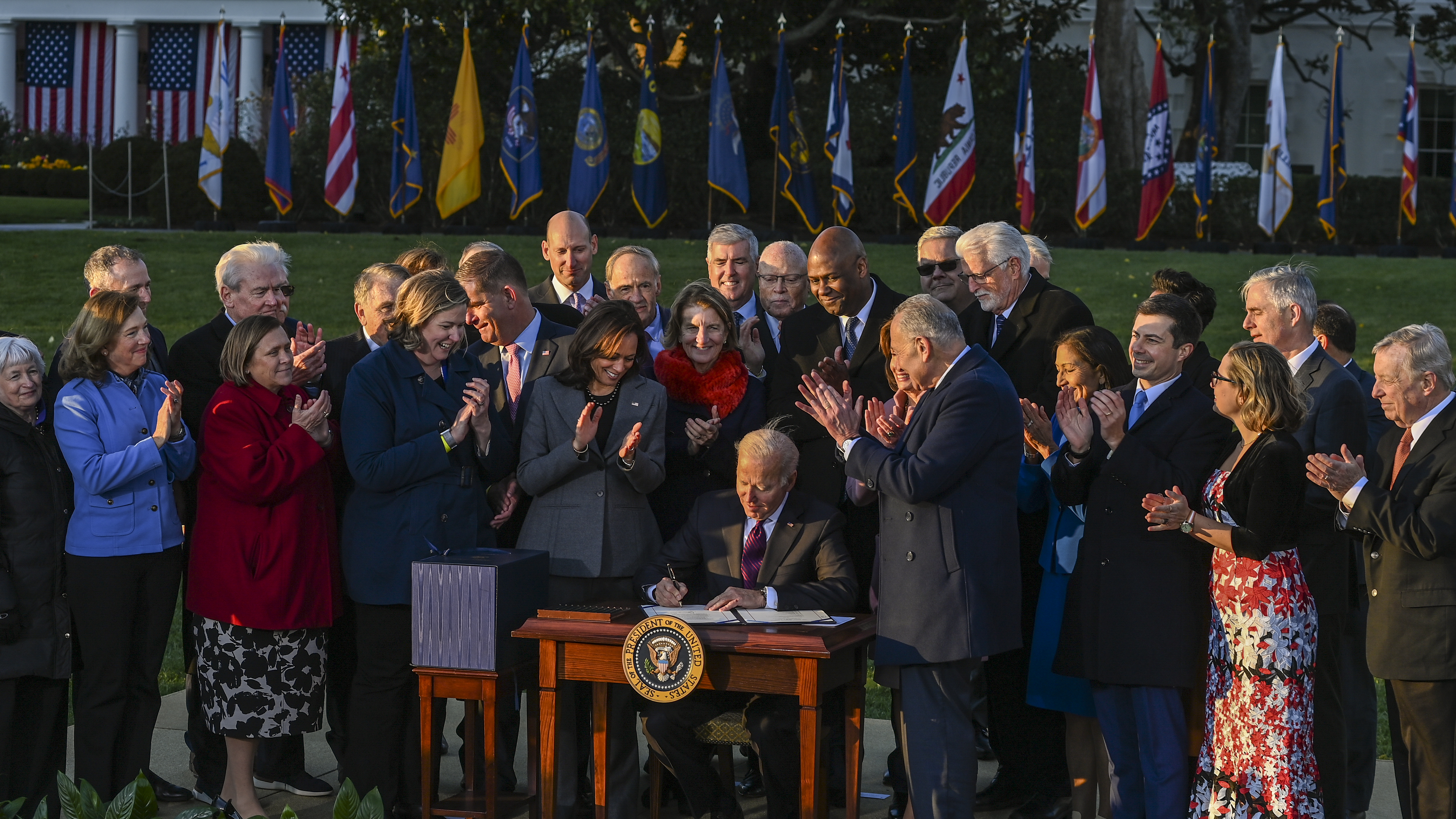 President Biden signs the Infrastructure Investment and Jobs Act as he is surrounded by lawmakers and members of his Cabinet during a ceremony on the South Lawn at the White House on Monday.