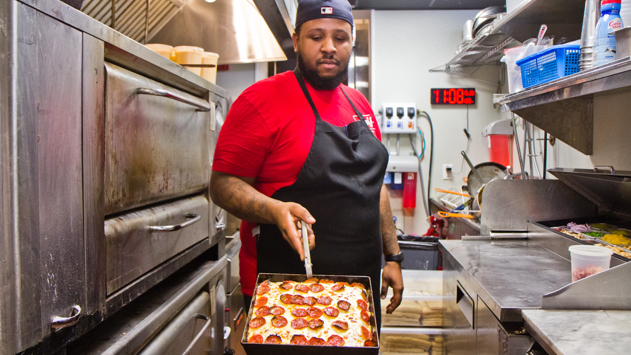 Down North Pizza employee Myles Jackson presents a pie from the oven.