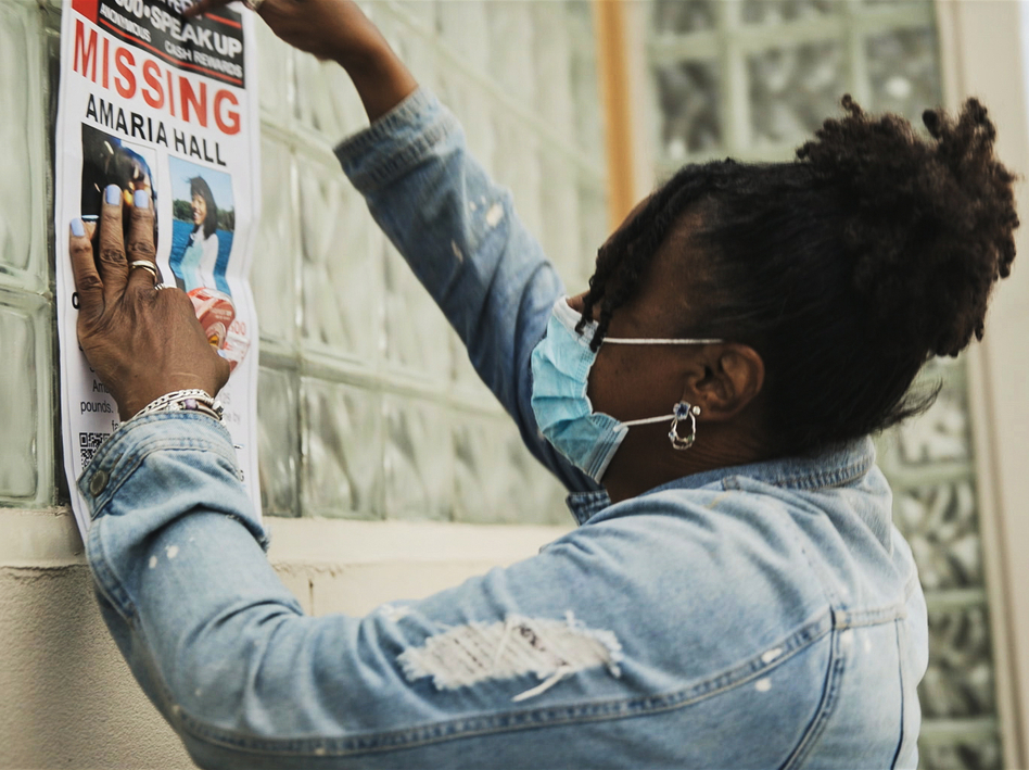 A community member posts flyers for Amaria Hall. (Courtesy of HBO)
