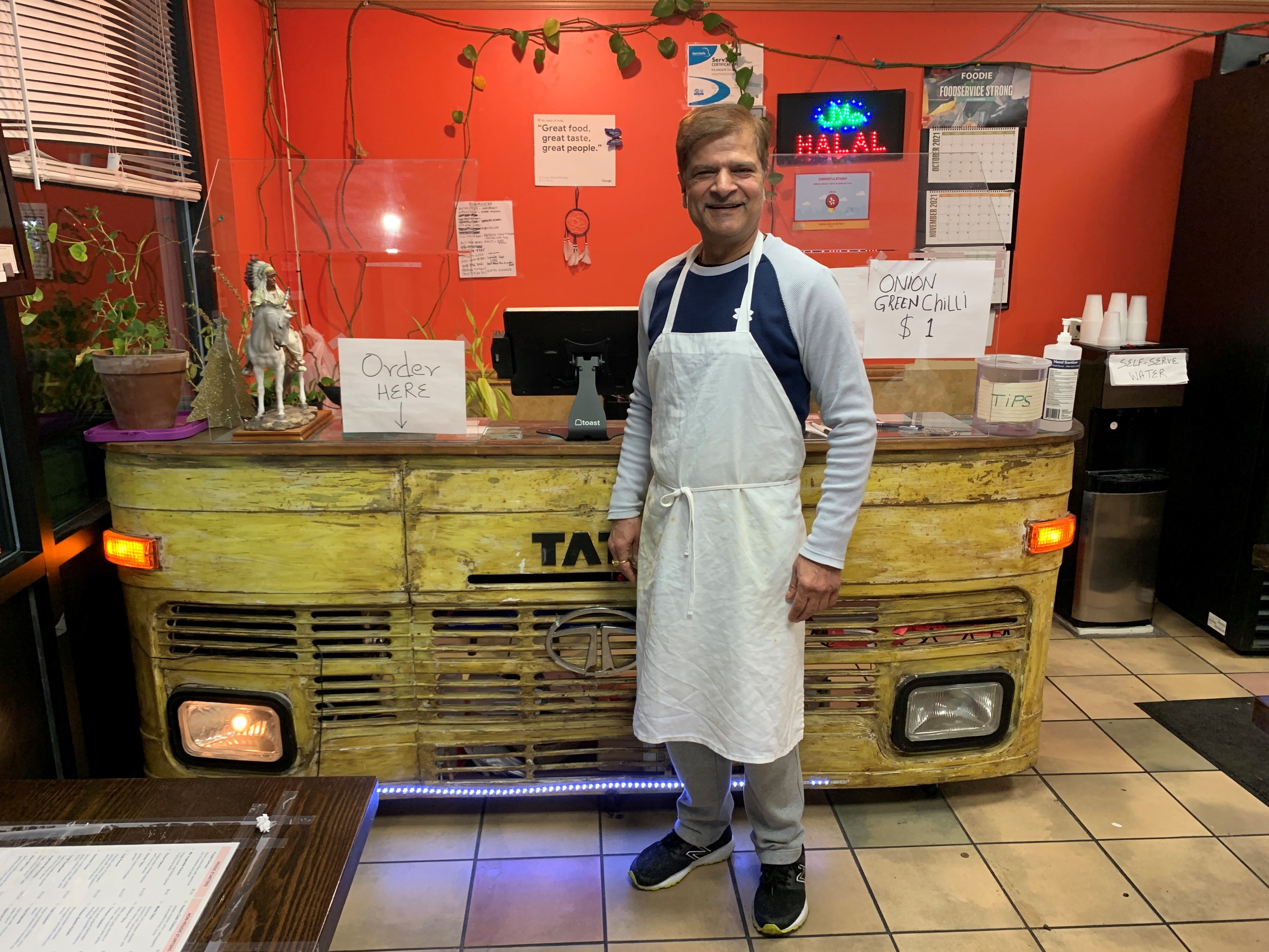 Jagdeep Nayyar, owner and chef at My Taste of India, stands in front of the register stand that's made from the front panel of a real Tata truck — the best-selling brand in India. (Joel Rose)