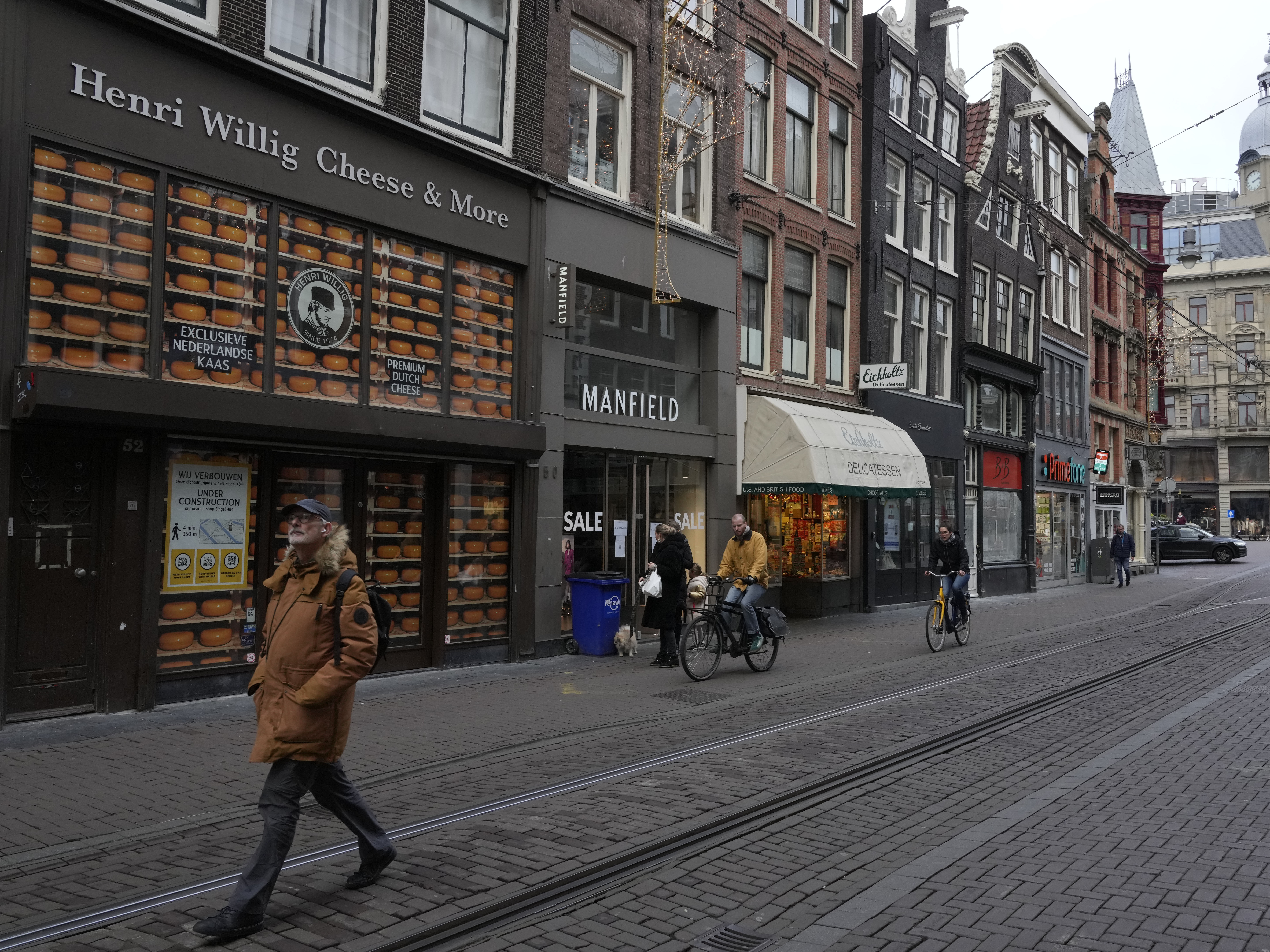 A man walks by a closed cheese store on a normally bustling shopping street in the center of Amsterdam on Monday. Nations across Europe have moved to reimpose tougher measures to stem a new wave of COVID-19 infections spurred by the highly transmissible omicron variant. Netherlands has imposed a nationwide lockdown.