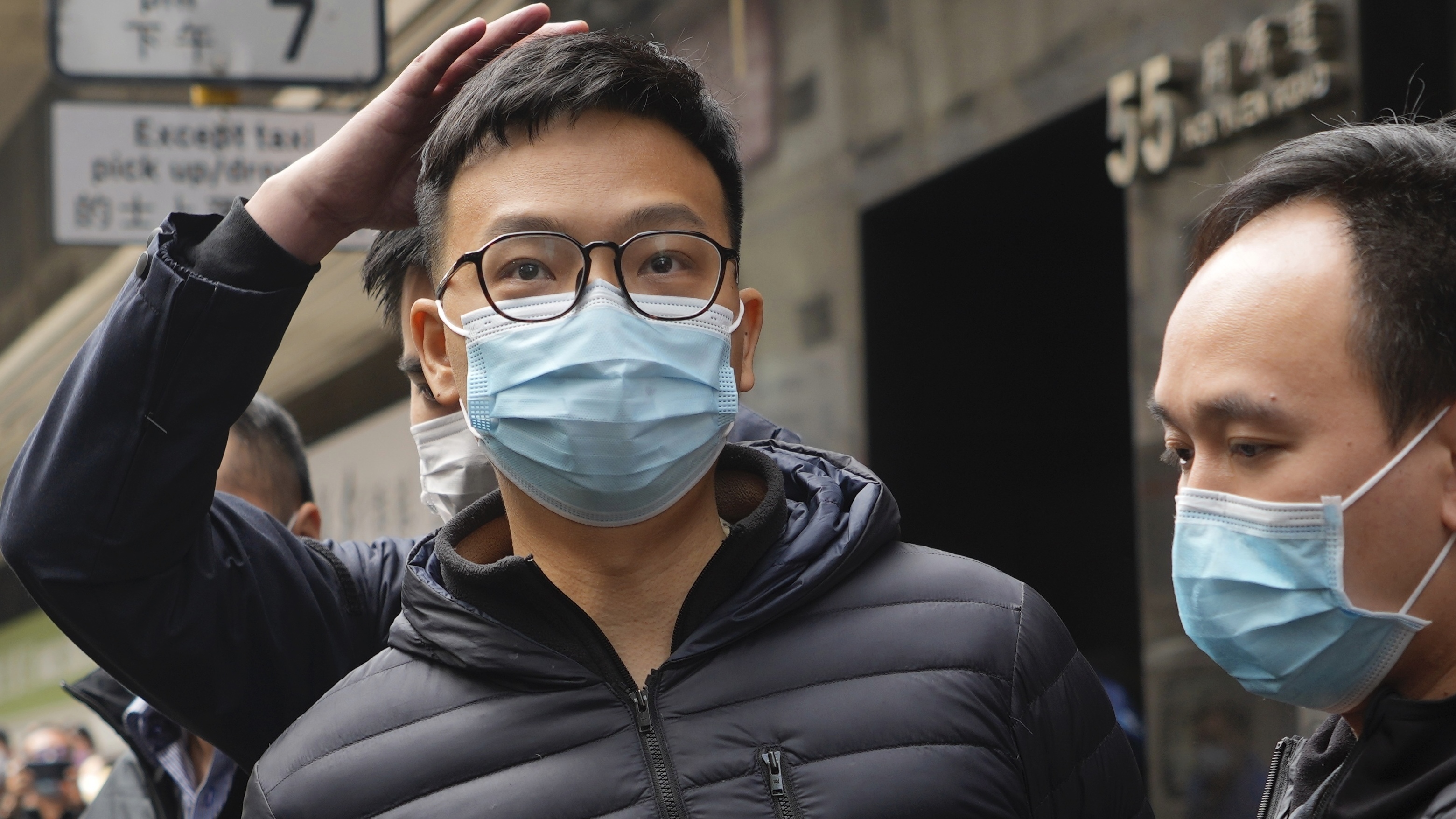 Patrick Lam, an editor at Stand News, is escorted into a van by police officers after they searched for evidence at his office in Hong Kong, Wednesday, Dec. 29, 2021.