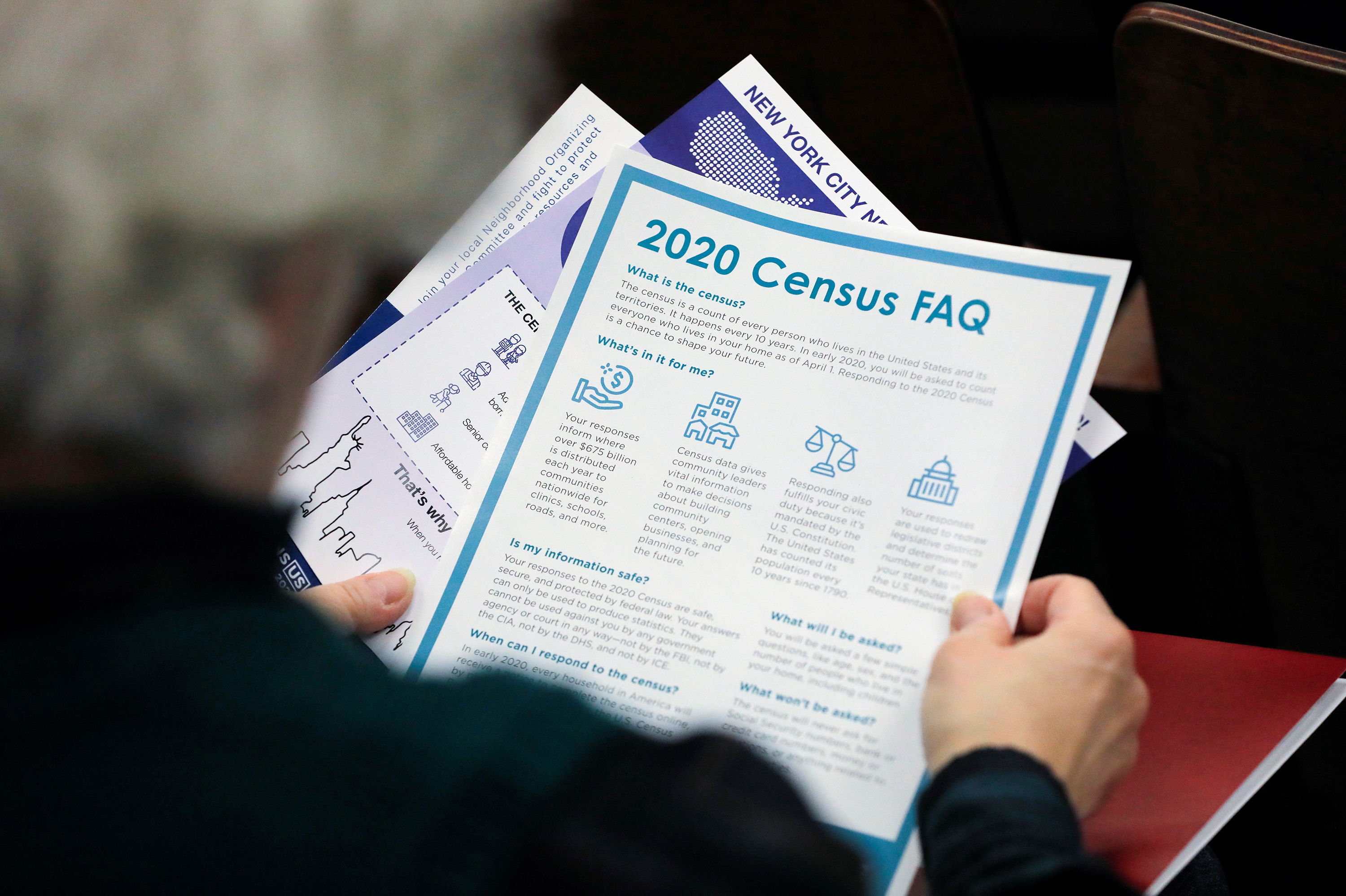 A person holds a flyer explaining the benefits of participating in the census during a 2020 town hall in East Elmhurst, N.Y. (Reuters)