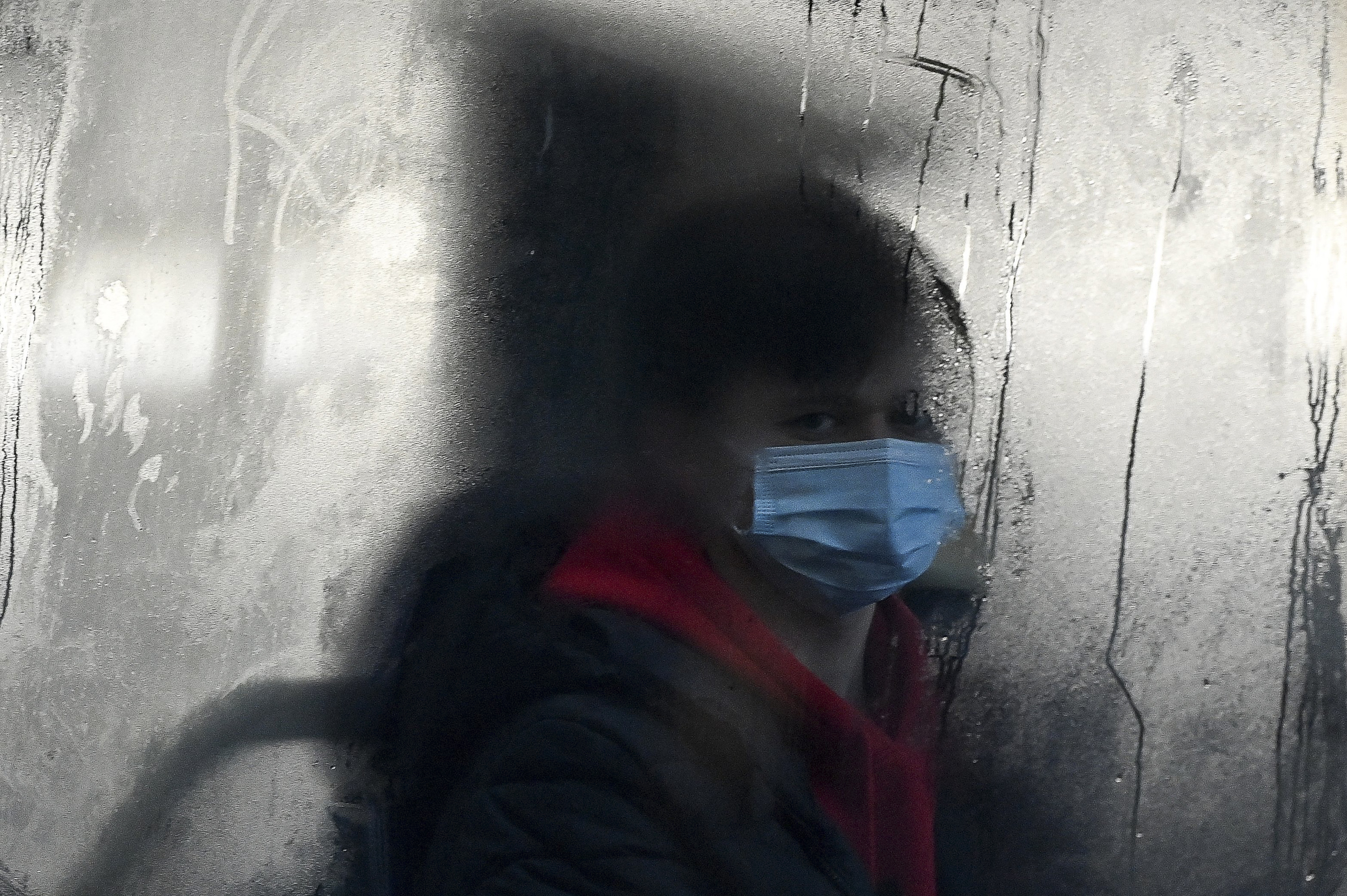 A commuter masks up for a bus ride in Liverpool, England. The omicron variant of the coronavirus has surged in the U.K. and is now dominant in the U.S. as well. There's now data indicating just how severe its symptoms might be. (AFP via Getty Images)