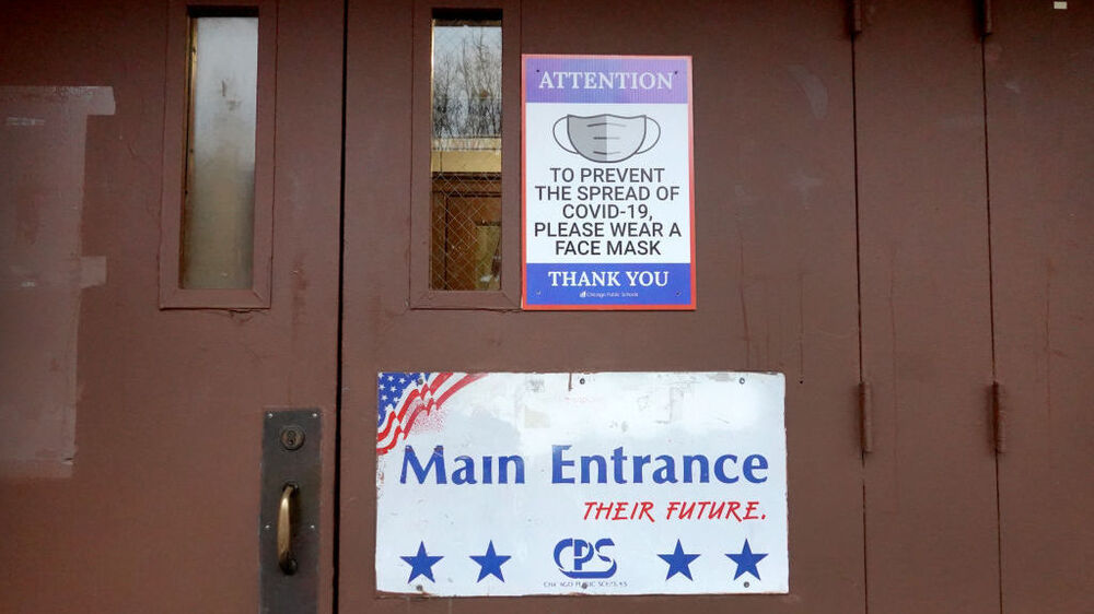 A sign on the door of Lowell Elementary School asks students, staff and visitors to wear a mask to prevent the spread of COVID-19 on Wednesday in Chicago. Classes at all of Chicago public schools have been canceled Wednesday by the school district after the teachers union voted to return to virtual learning. (Getty Images)