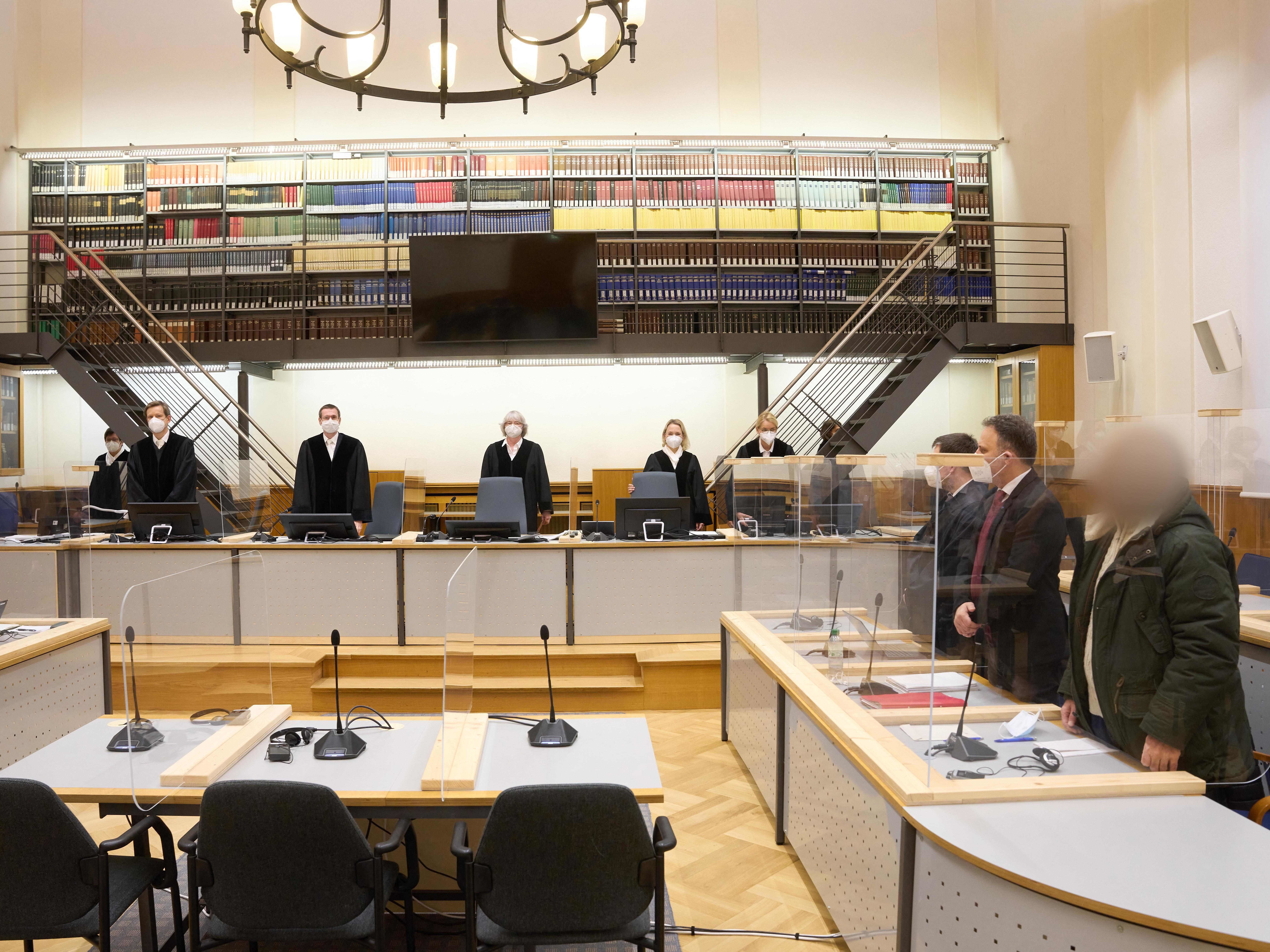 Defendant Anwar Raslan (right) and others involved in his trial stand in the Higher Regional Court in Koblenz, Germany, at the start of a trial session last month. Raslan was put on trial in April 2020 in a landmark case in Germany. (Pool/AFP via Getty Images)