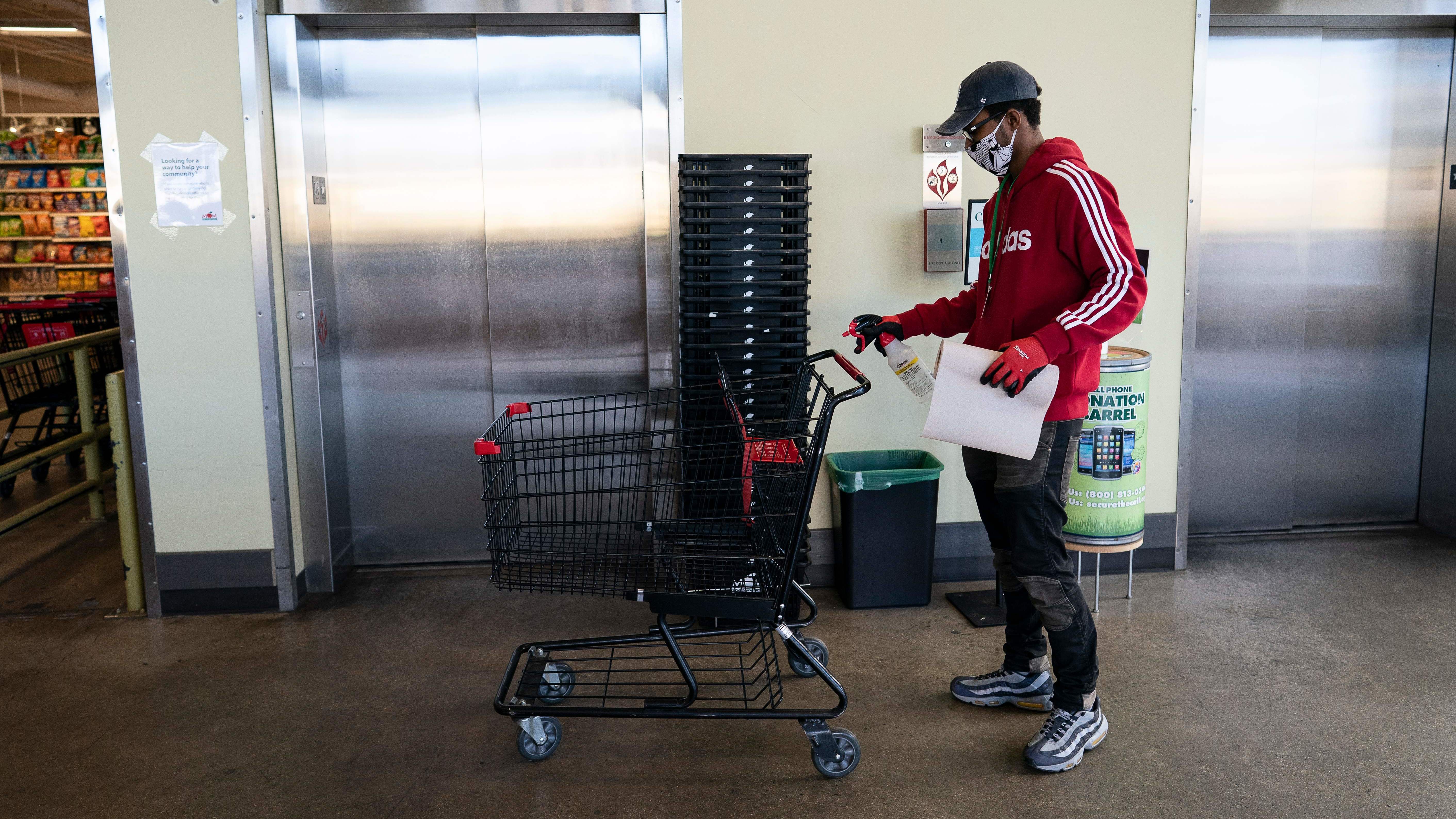 A grocery store worker sanitizes a shopping cart at a MOM's Organic Market in Washington, D.C., in April 2020.