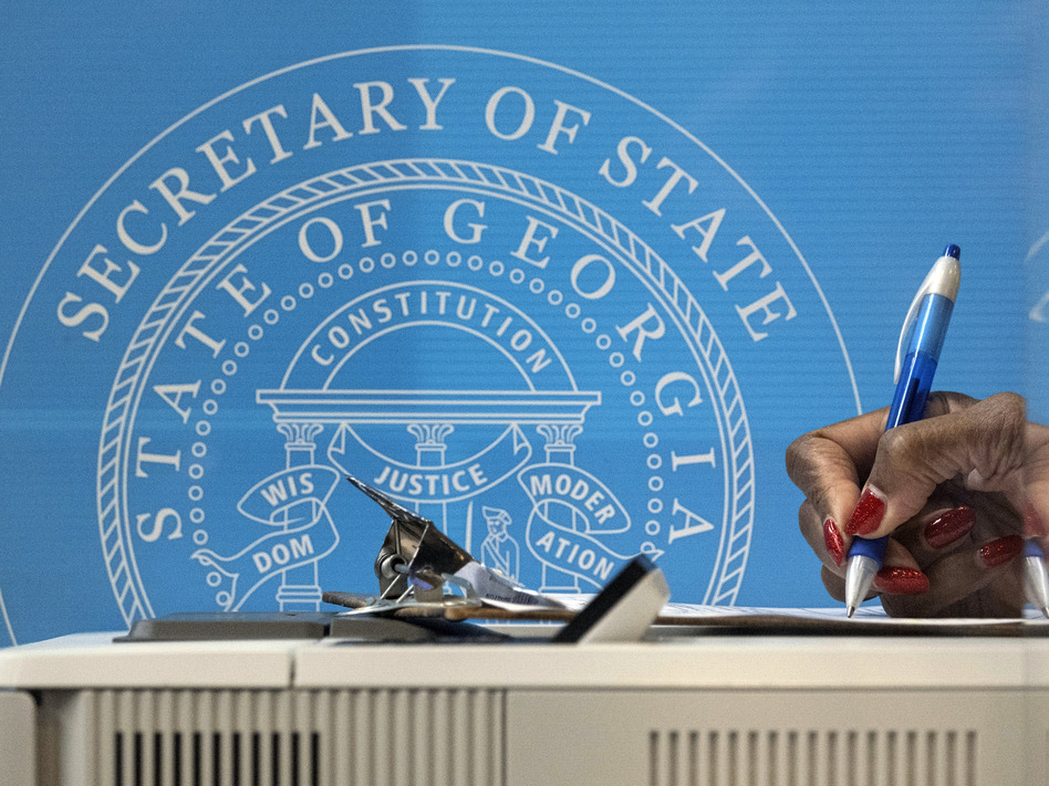 In this Dec. 14, 2020, file photo, a voter fills out paperwork before casting a ballot the first day of early voting for the Senate runoff election in Atlanta. (Ben Gray/AP)