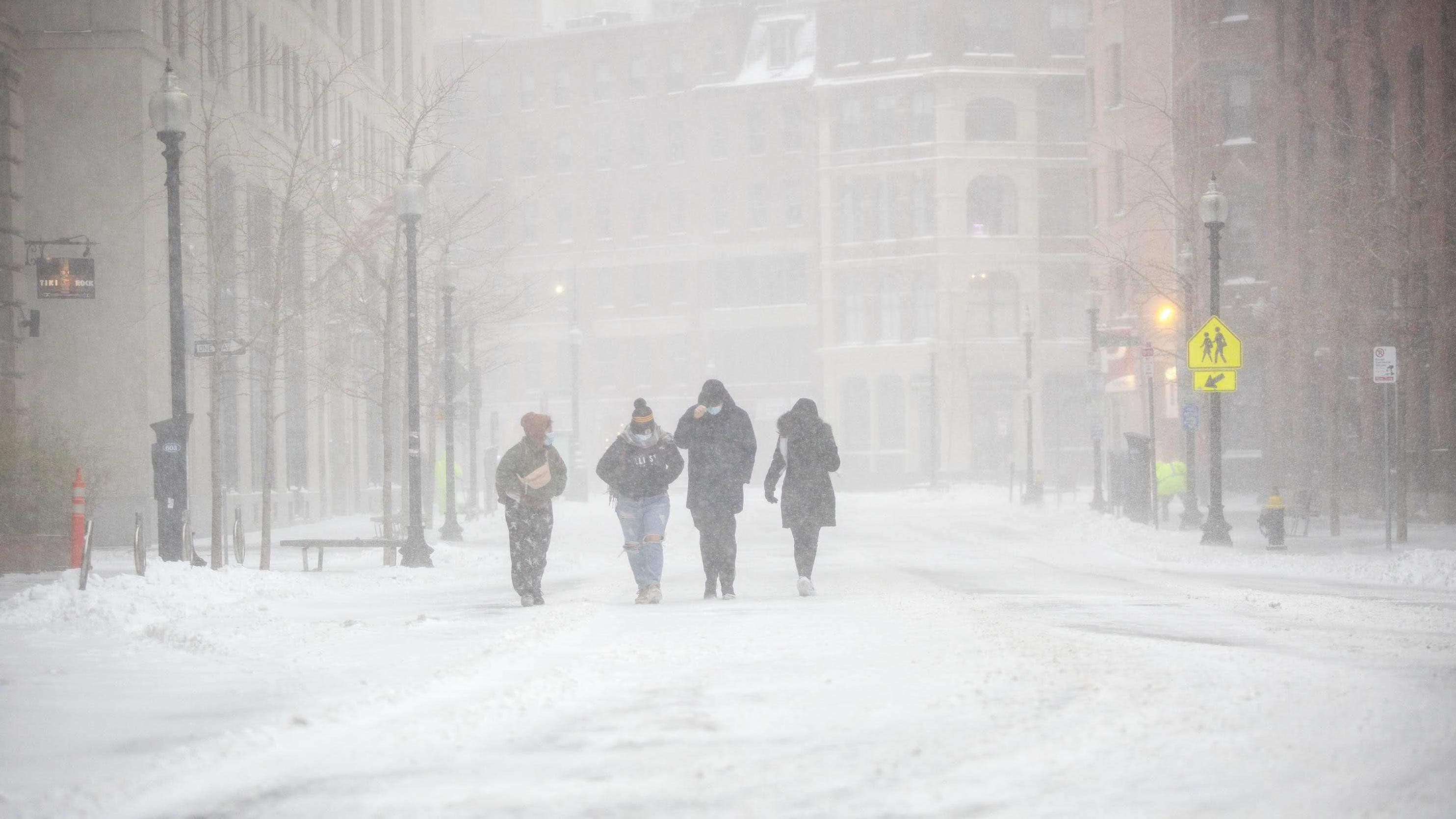 A group of people battle with wind and snow as they make their way along Broad Street in Boston.