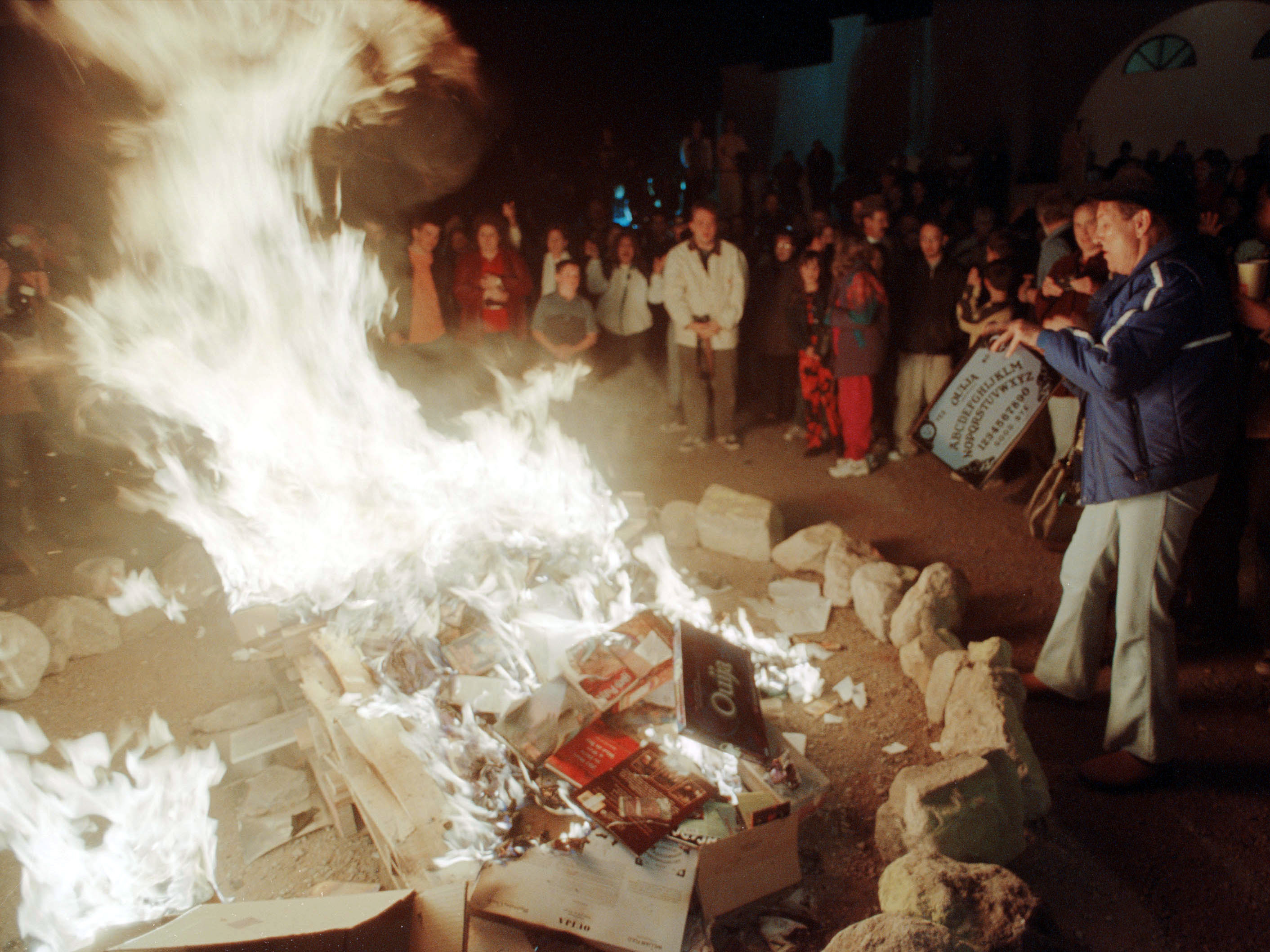 A woman tosses a Ouija Board into a bonfire outside a church in New Mexico in 2001, after  the church's pastor urged parishioners to burn dozens of Harry Potter books and other types of literature and games they found offensive. (Getty Images)