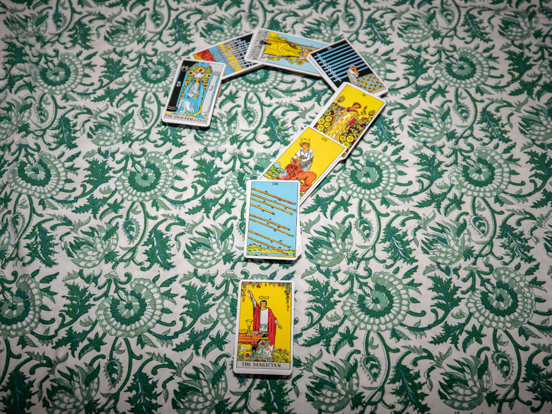 Tarot cards arranged in the shape of a question mark on a patterned floral tablecloth.