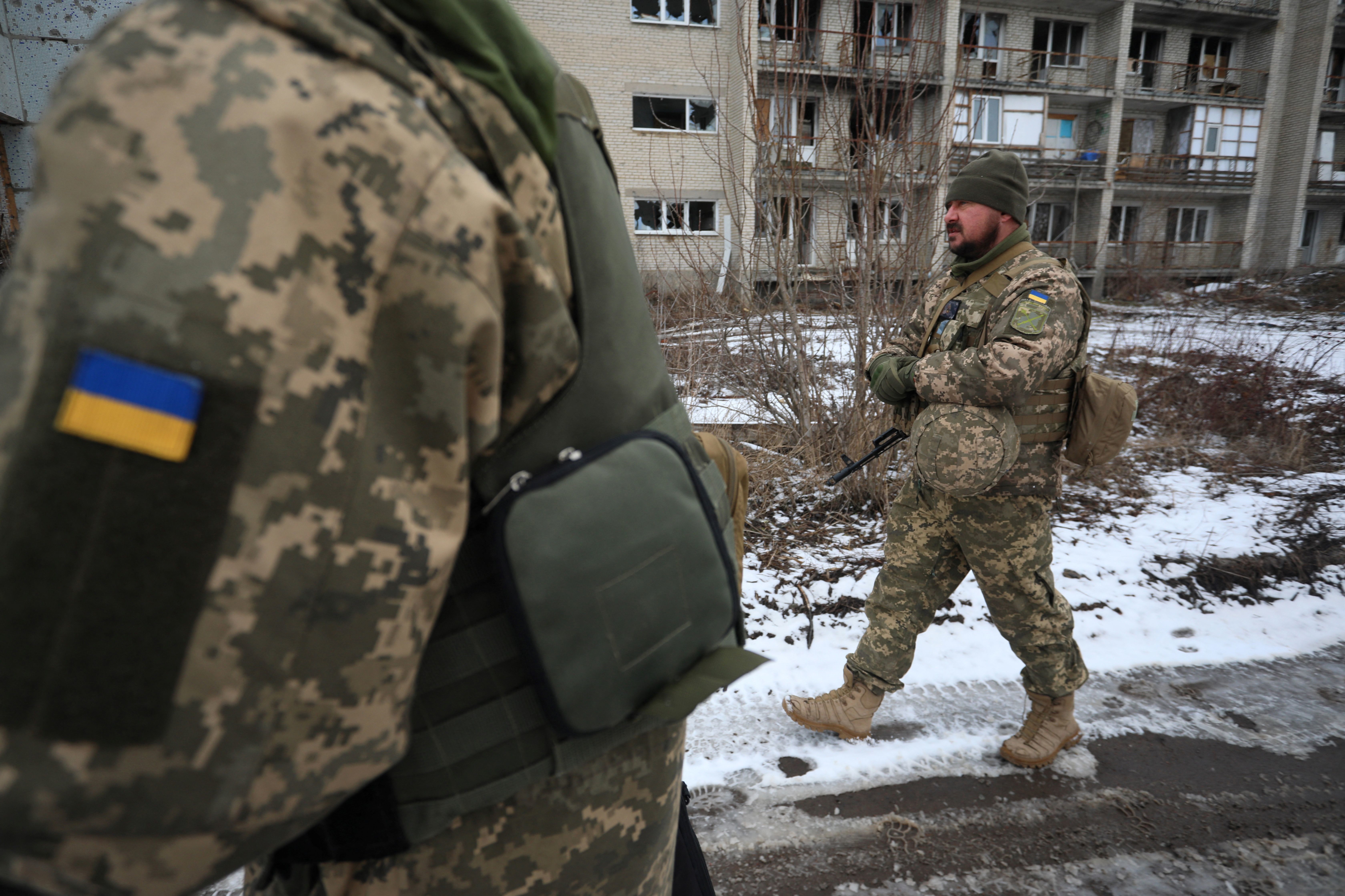 Ukrainian military forces walk in front of damaged buildings on the front line with Russia-backed separatists in Mariinka in the Donetsk region on Feb. 7. (AFP via Getty Images)