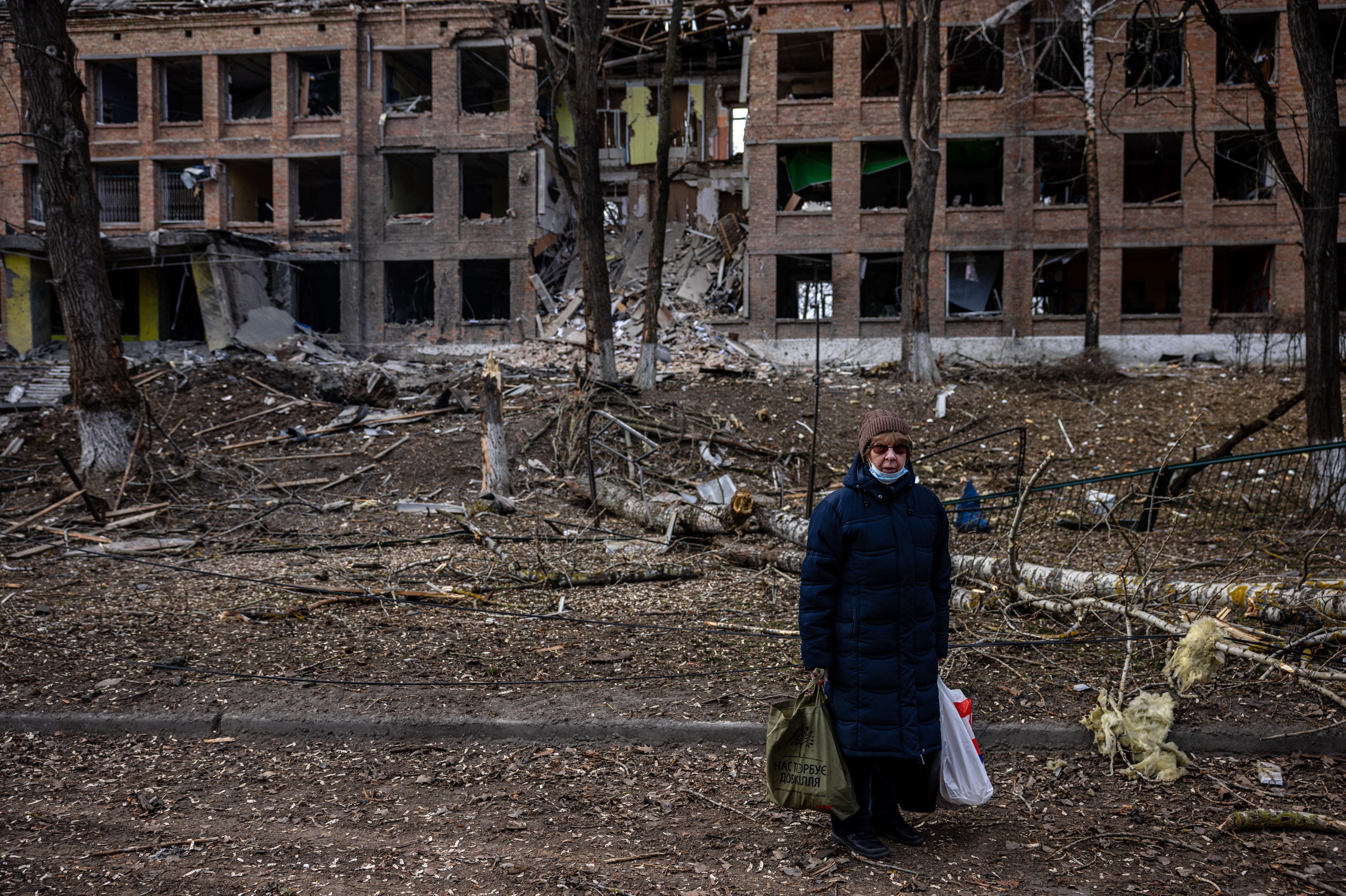 A woman stands in front of a destroyed building after a Russian missile attack in the town of Vasylkiv, near Kyiv, on  Sunday. Russian forces faced stiff resistance over the weekend and faced logistics problems in their invasion plans. (AFP via Getty Images)