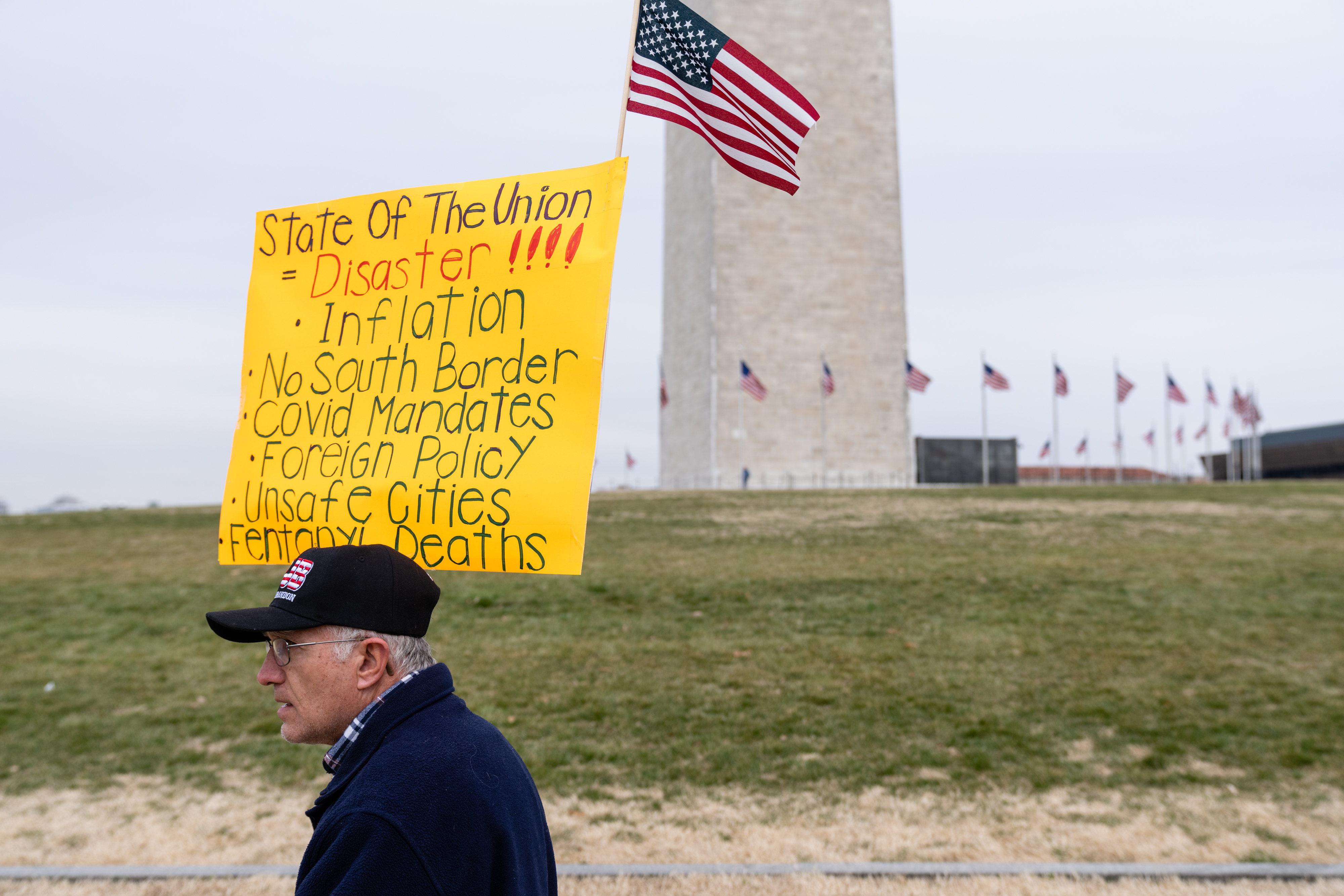 A protester holds a sign ahead of President Biden's State of the Union speech near the Washington Monument in Washington, D.C., on Tuesday. Biden will need to rediscover his foreign policy expertise and deft touch with everyday Americans, qualities that polls show many voters now doubt, in his first State of the Union speech. (Bloomberg via Getty Images)