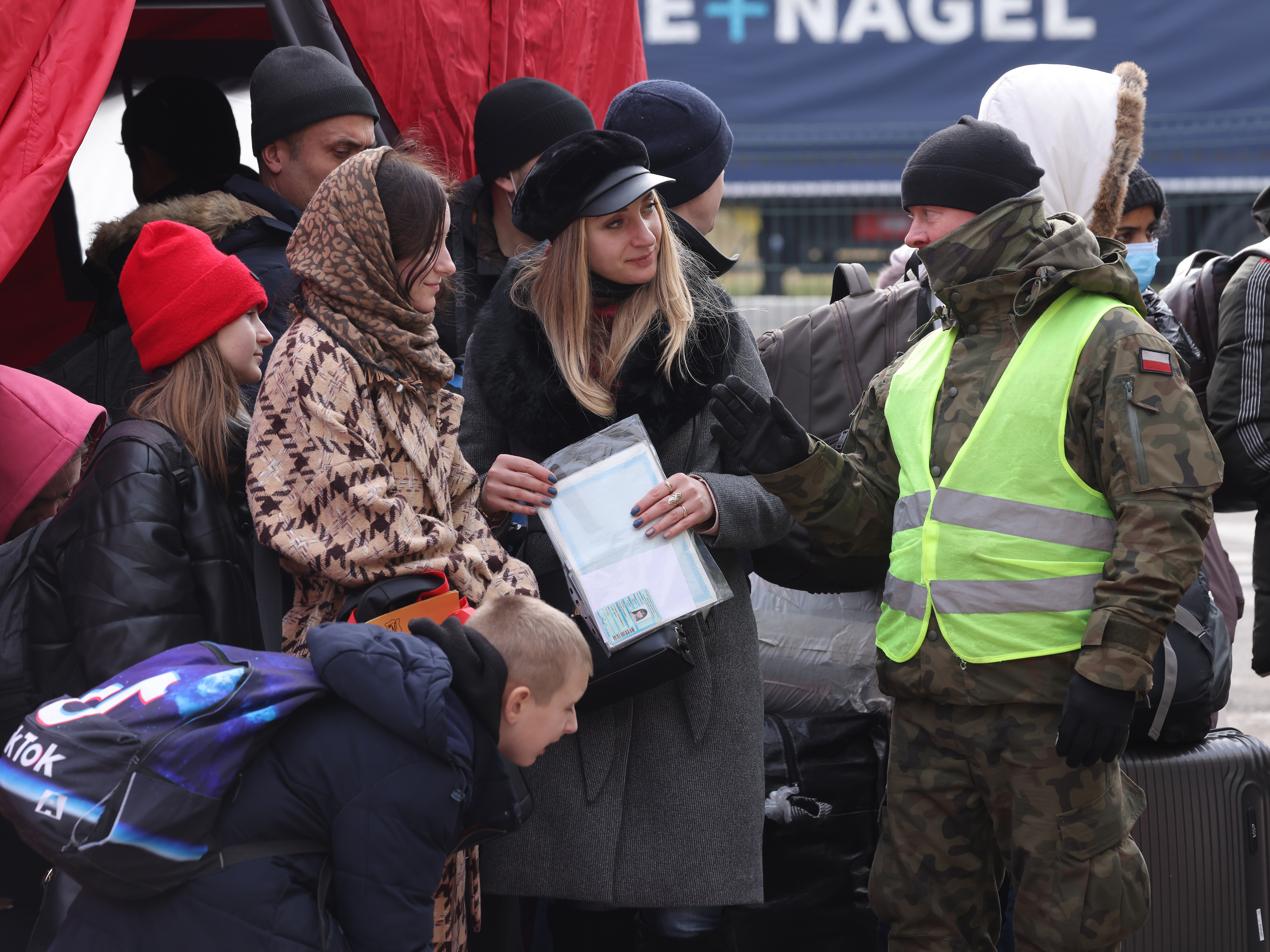 A Polish border guard speaks with women and children fleeing Ukraine at a border crossing on Wednesday near Korczowa, Poland. (Getty Images)