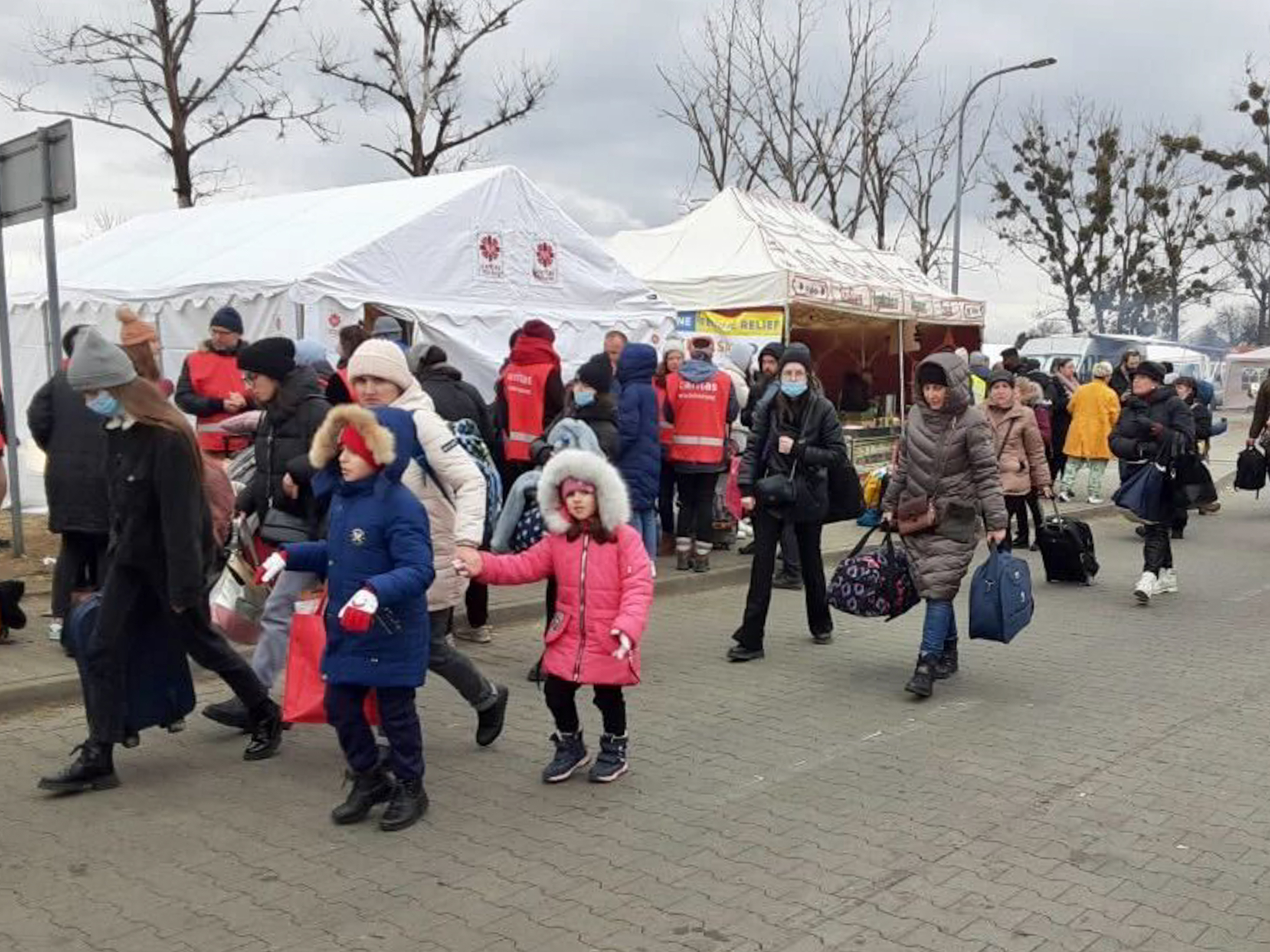Volunteers from Italy usher refugees from the Ukrainian city of Ivano-Frankivsk to a bus for transport to the northern Italian city of Cortina at a refugee center near Przemyśl, Poland. (NPR)
