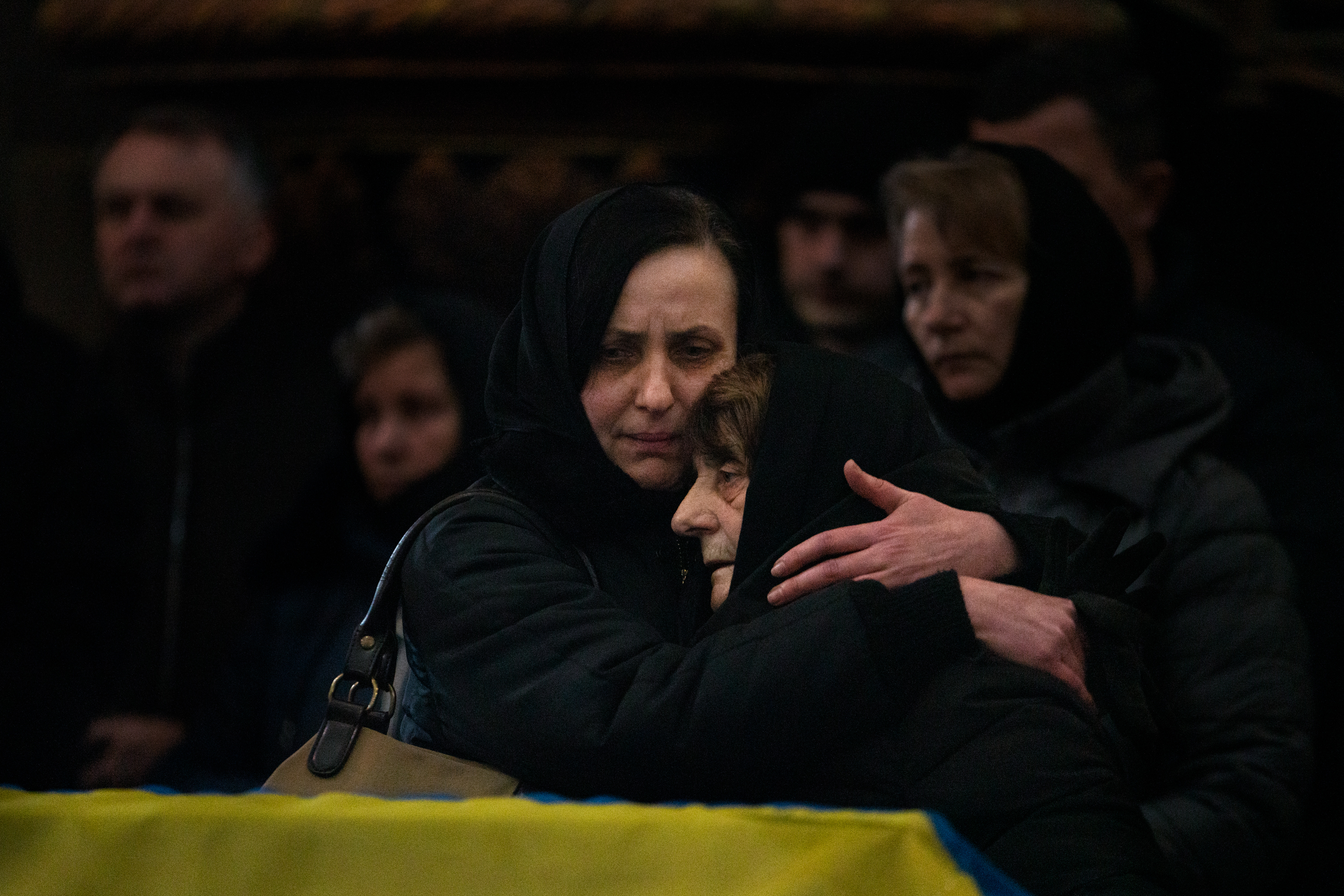 Oksana Dudar, left, the wife of Viktor Dudar, hugs her mother-in-law at her husband's funeral Tuesday in Lviv, Ukraine. Viktor was a soldier who was killed by Russian forces. A U.S. defense analyst estimates more than 1,500 were killed in the first five days of the war. The Ukrainian military tells NPR it isn't disclosing the number of soldiers lost in the fight with Russia. (NPR)