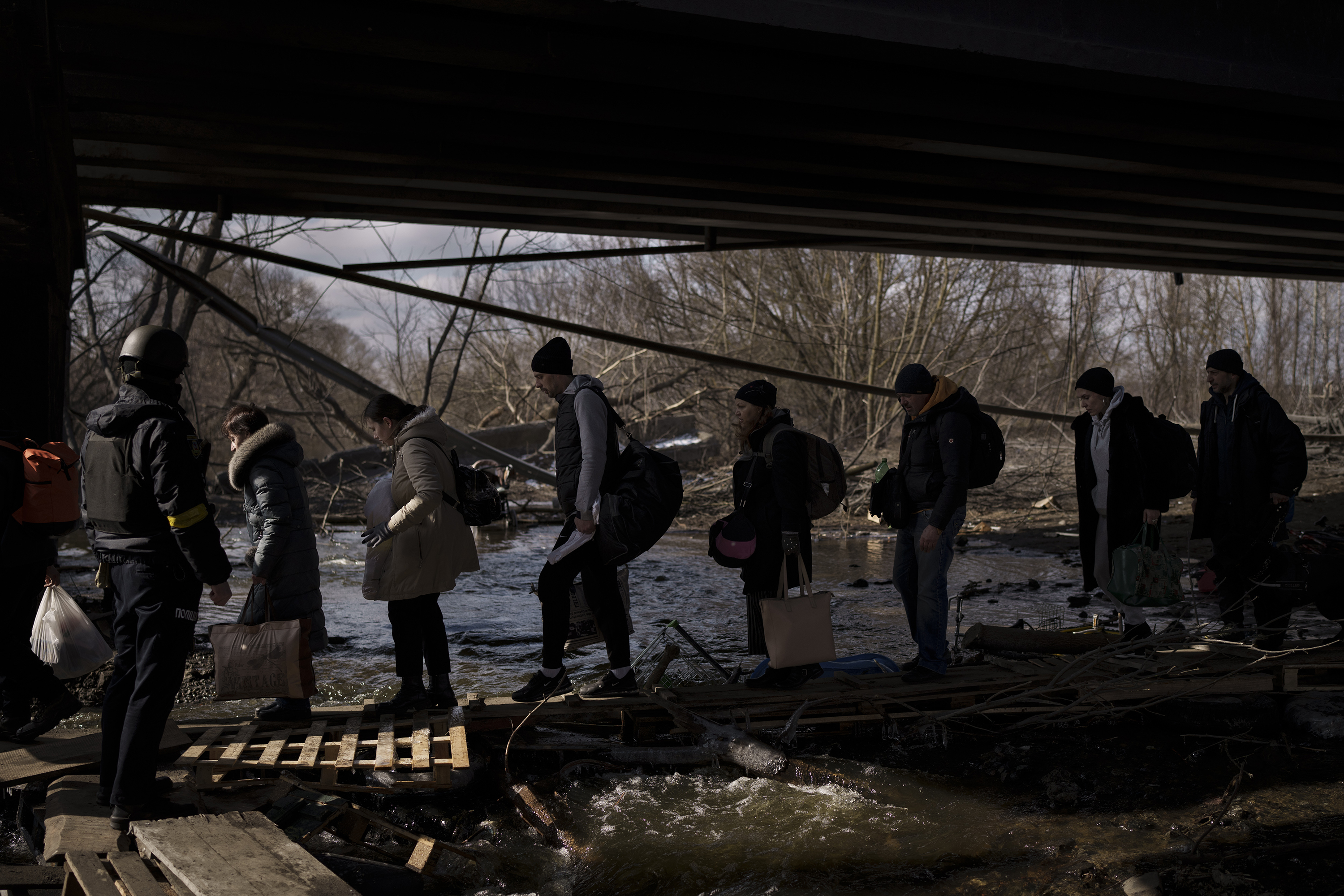 March 9: Ukrainians cross an improvised path under a destroyed bridge while fleeing Irpin.