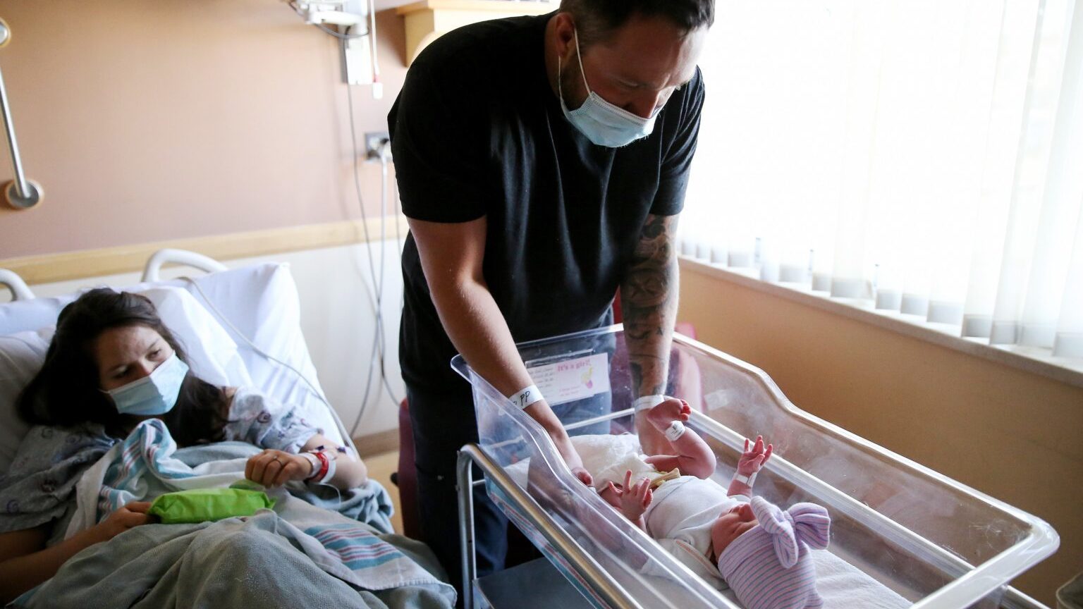 Matthew Carnes prepares to change diapers for his newborn daughter Evelina Carnes as his wife Breanna Llamas keeps watch in the postpartum unit at Providence St. Mary Medical Center. (Getty Images)