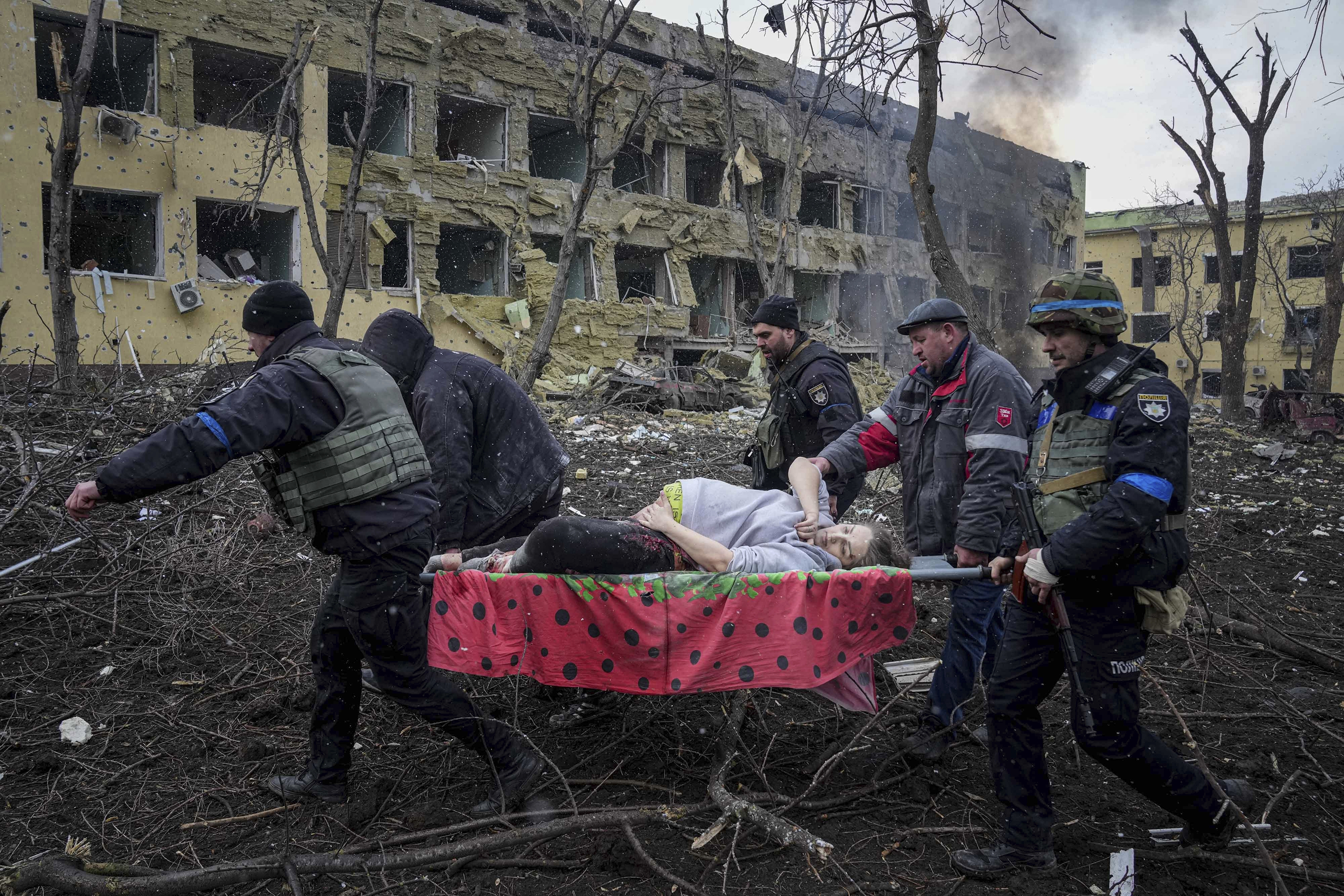 March 9: Ukrainian emergency employees and volunteers carry an injured pregnant woman from a maternity hospital in Mariupol, Ukraine. Ukrainian officials say Russian forces shelled the building in the besieged port city.