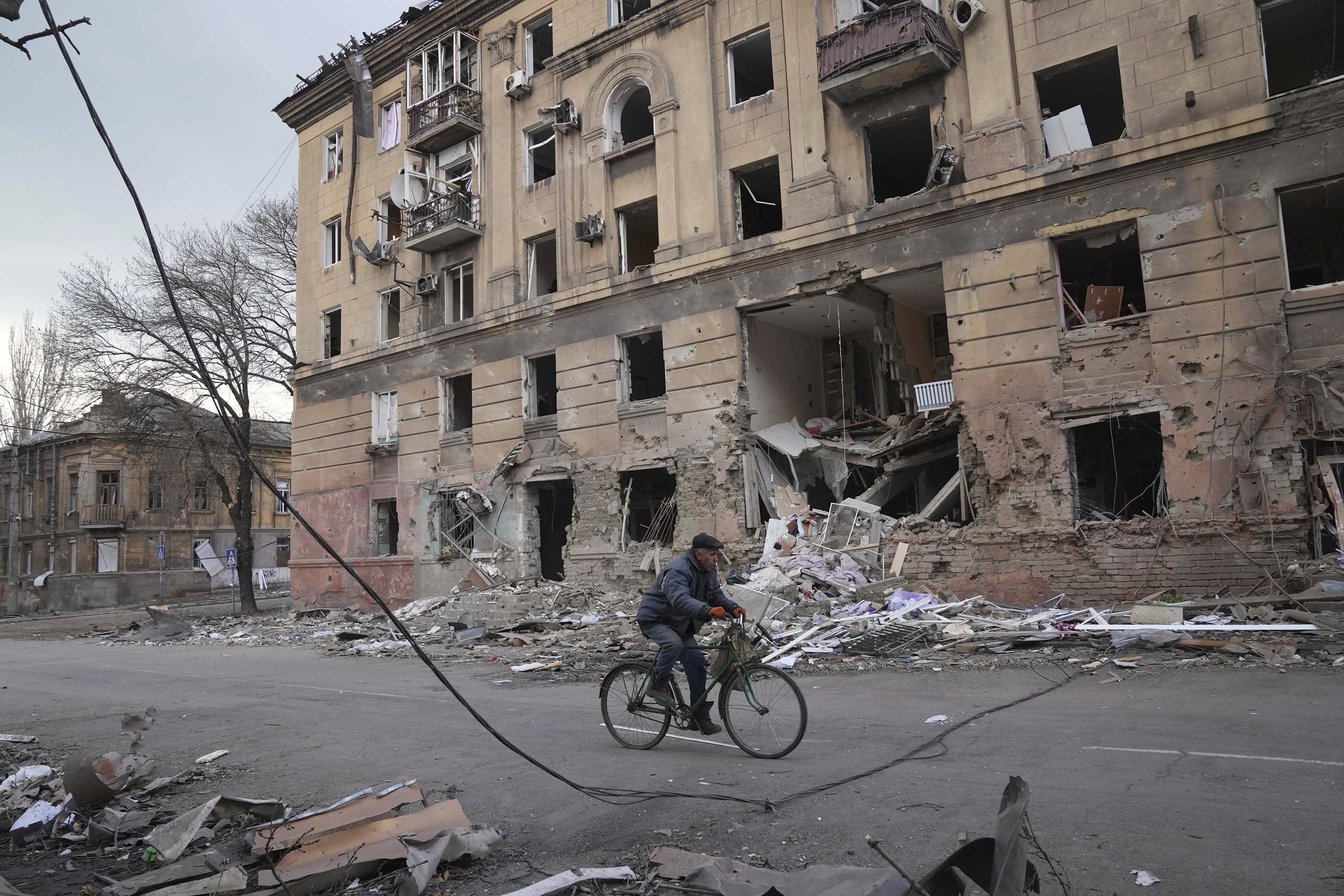 March 9: A man rides a bicycle in front of an apartment building that was damaged by shelling in Mariupol, Ukraine.