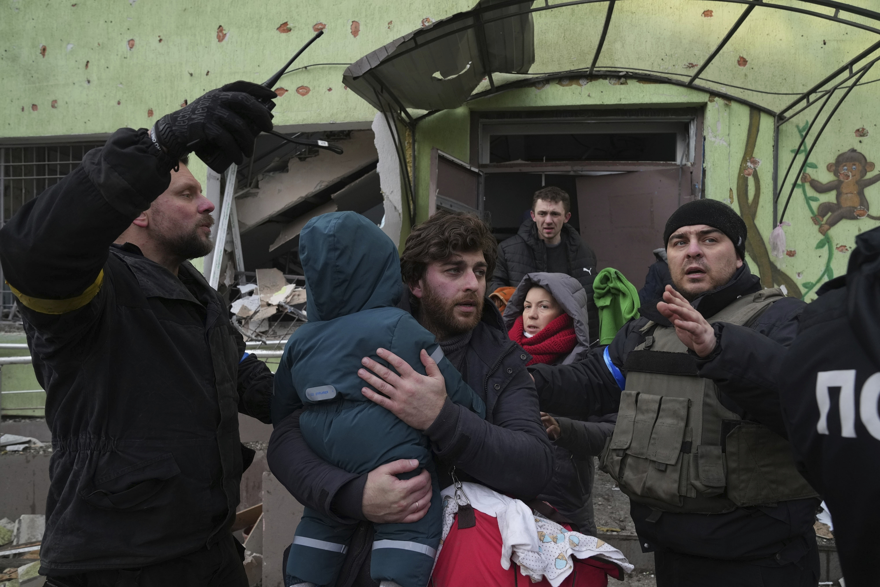 March 9: A man carries his child away from a damaged maternity hospital in Mariupol.