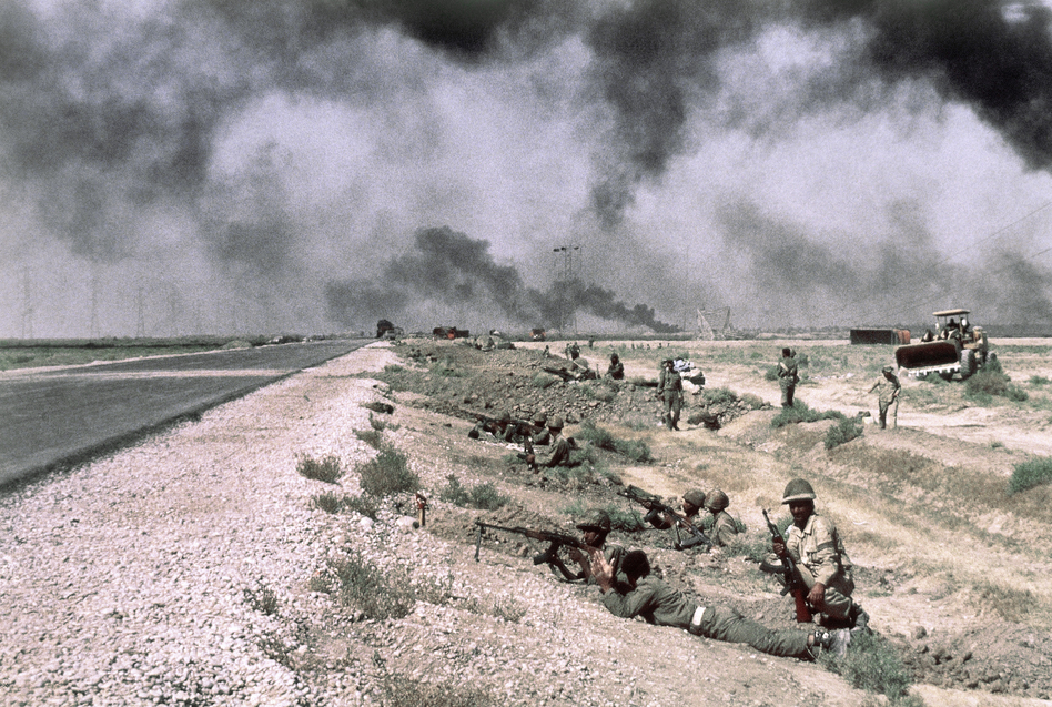Iraqi troops are beside a roadway in Iran on Oct. 17, 1980. The smoke in the background is from fires along pipelines used to carry oil from the giant refinery at Abadan to Ahwaz and Tehran.