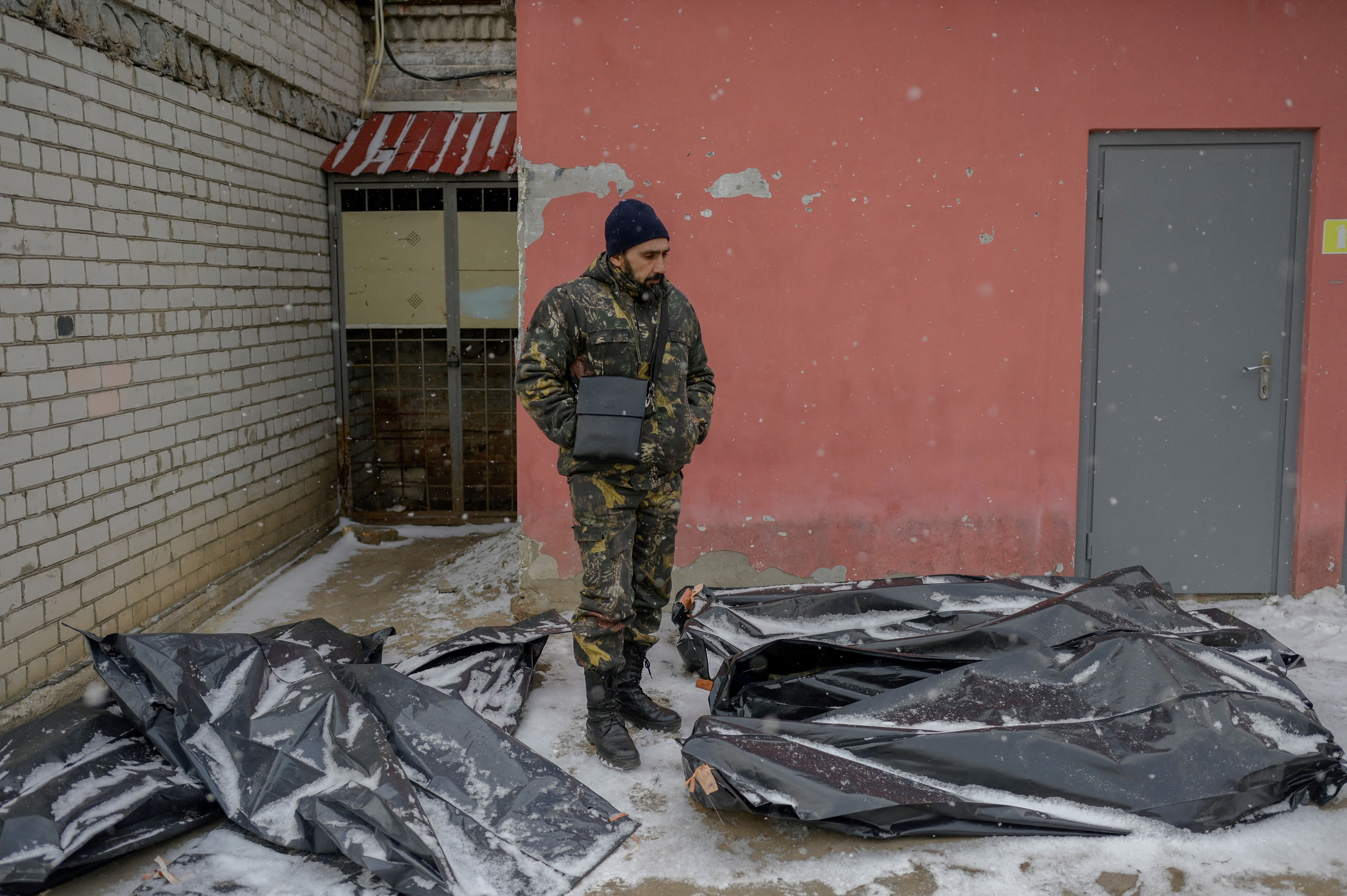 March 11: A Ukrainian man in camouflage stands next to snow-covered body bags in the yard of a morgue in Mykolaiv, Ukraine, which sits on the shores of the Black Sea and has been under attack by Russian forces for days.