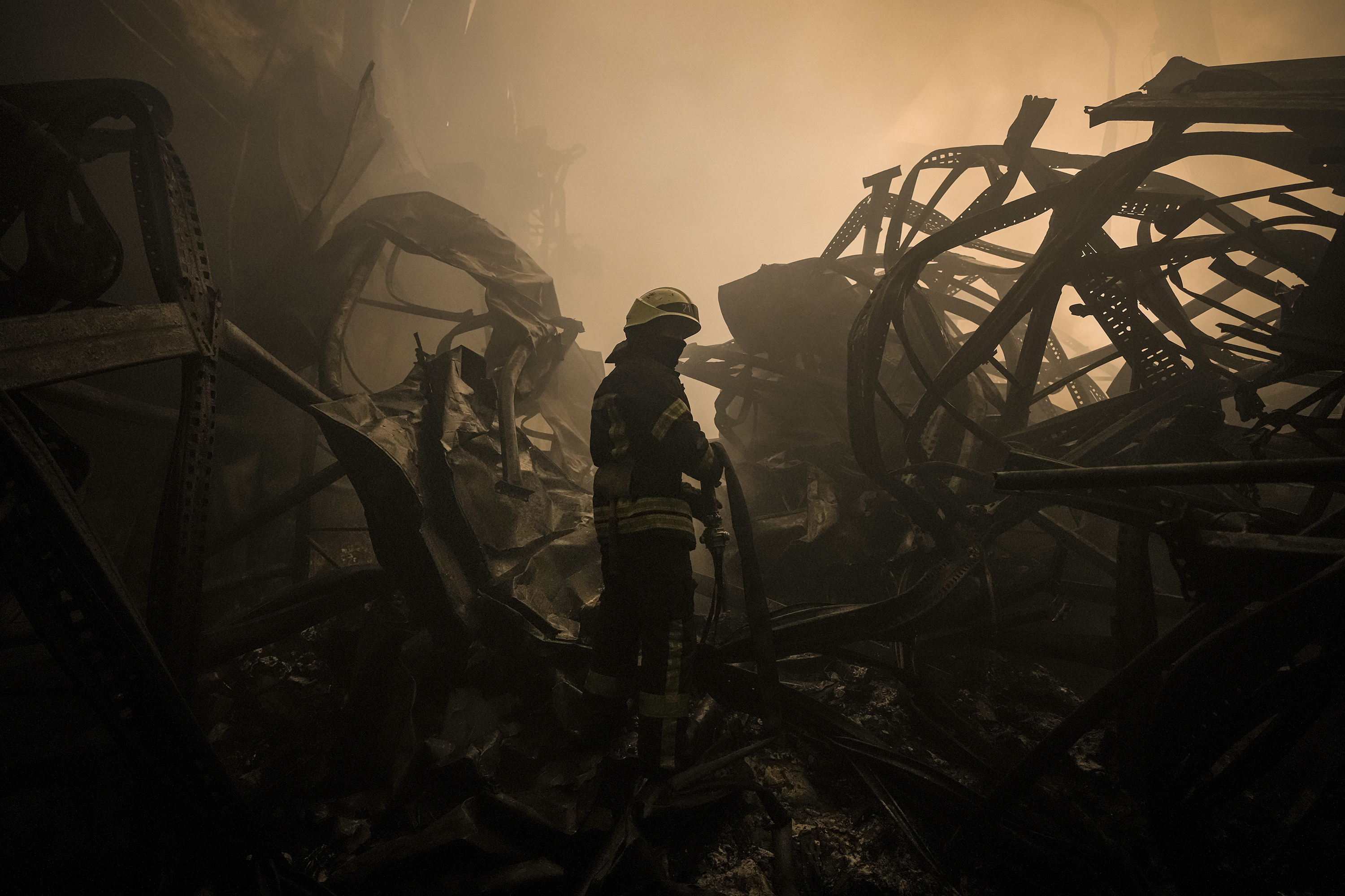 March 13: A firefighter drags a hose inside a large food storage facility that was destroyed by an airstrike in the early morning hours on the outskirts of Kyiv, Ukraine.