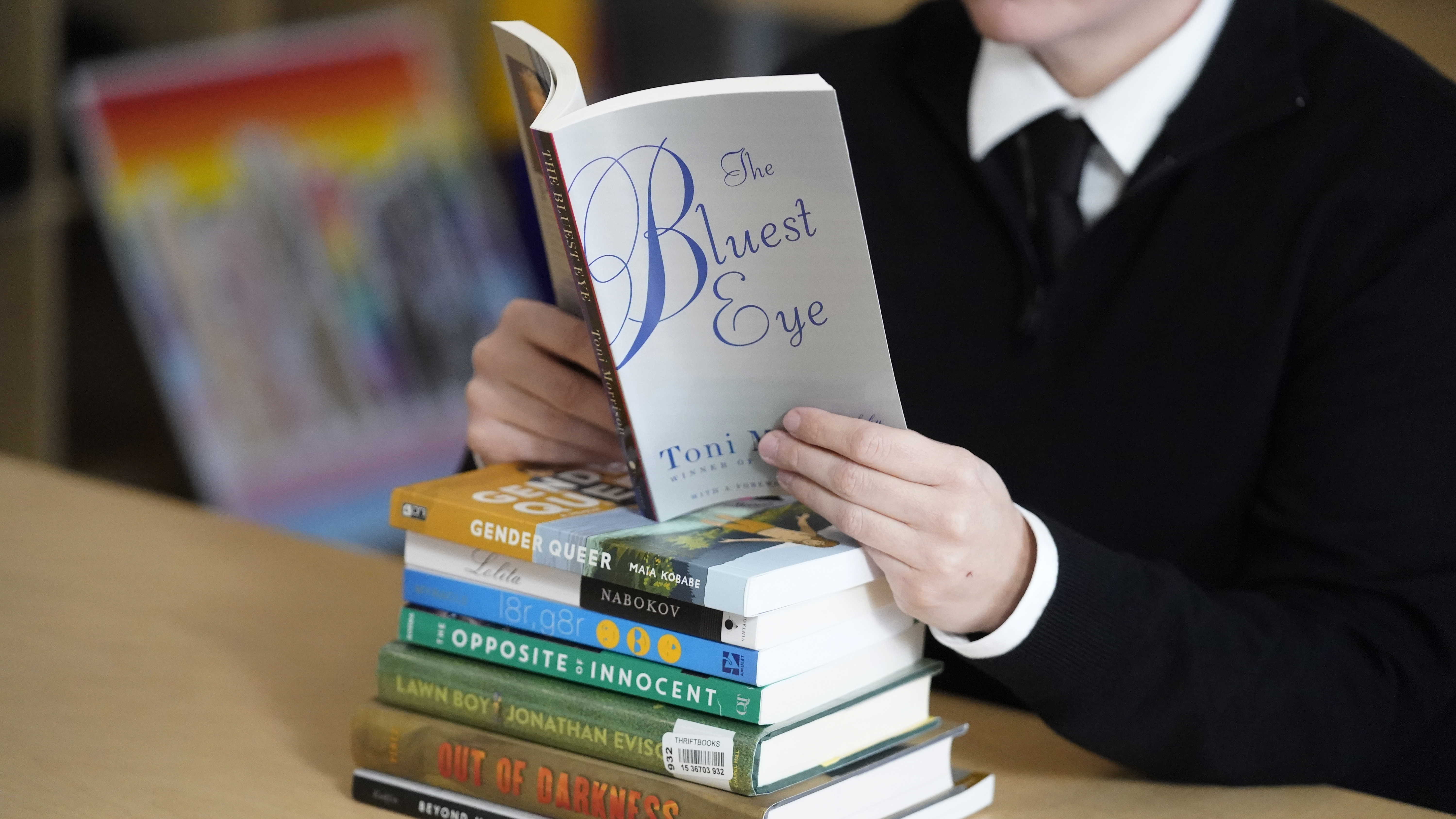 Amanda Darrow, director of youth, family and education programs at the Utah Pride Center, poses with books, including The Bluest Eye, by Toni Morrison and Lawn Boy by Jonathan Evison, that have been the subject of complaints from parents in Salt Lake City on Dec. 16, 2021.