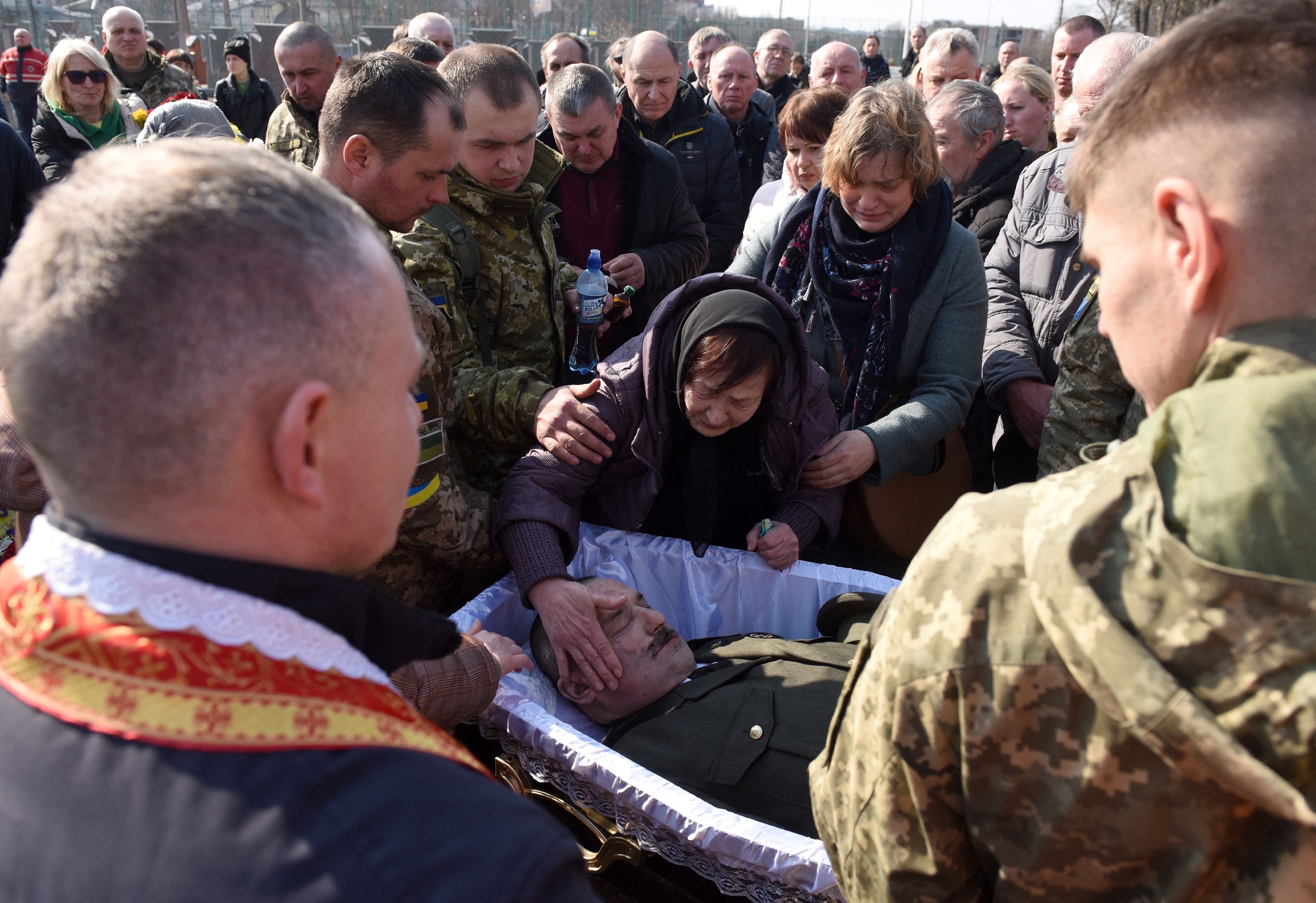 March 15: The mother of Col. Oleh Yaschyshyn reacts at the side of her son's coffin during funerals for Yaschyshyn, Sergiy Melnyk and Rostyslav Romanchuk — Ukrainian servicemen killed in Russia's invasion — at the Lychakiv cemetery in the western city of Lviv.