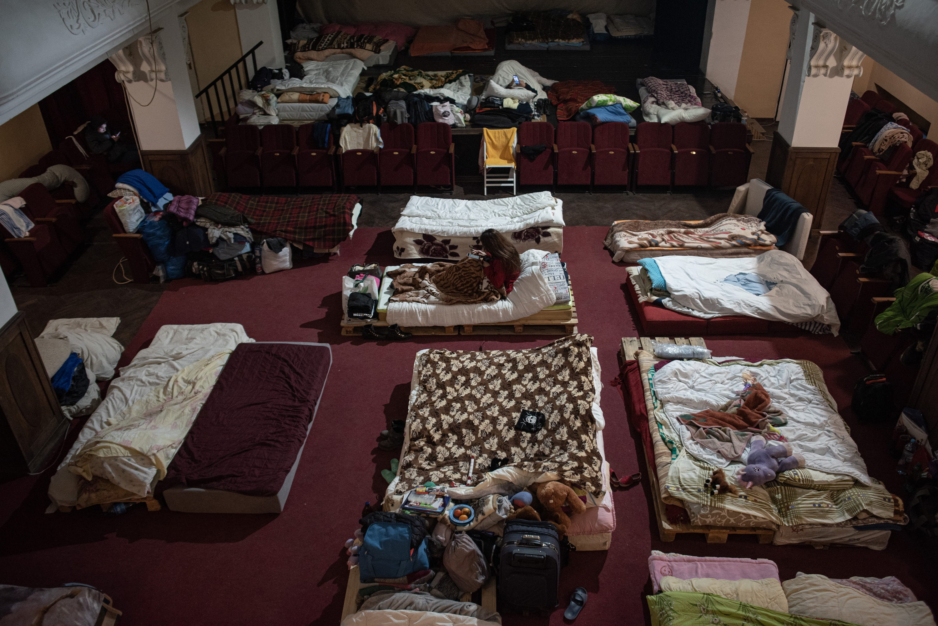 March 16: A woman sits on a makeshift bed in one of Lviv's theaters that's become a shelter in recent weeks. Lviv has served as a stopover and shelter for the millions of Ukrainians fleeing the invasion, either to the safety of nearby countries or the relative security of western Ukraine.