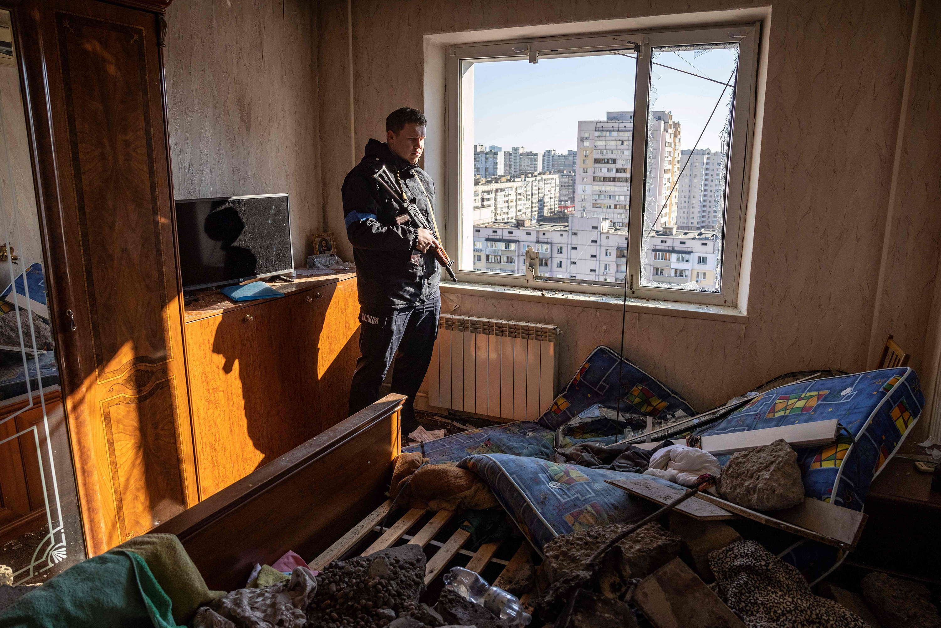 March 17: A police officer looks through the window of a damaged flat in a residential building that was hit by the debris of a downed rocket in Kyiv. One person was killed and three were injured when the debris hit an apartment block, according to Ukraine's emergency services.