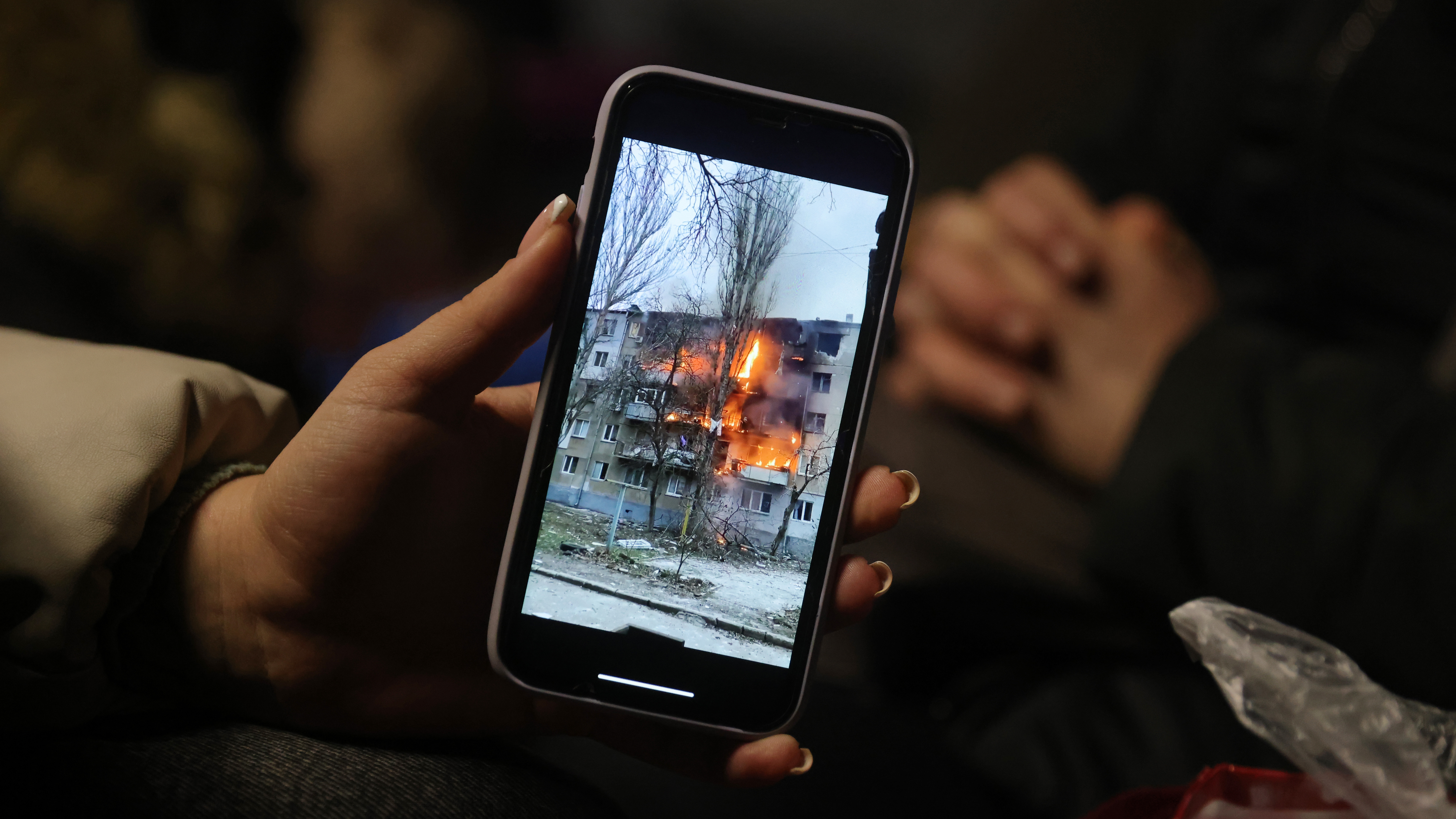 Iryna Holoshchapova, a Ukrainian refugee who fled the embattled city of Mykolaiv, shows a video on her smartphone of an apartment block on fire following a Russian attack.