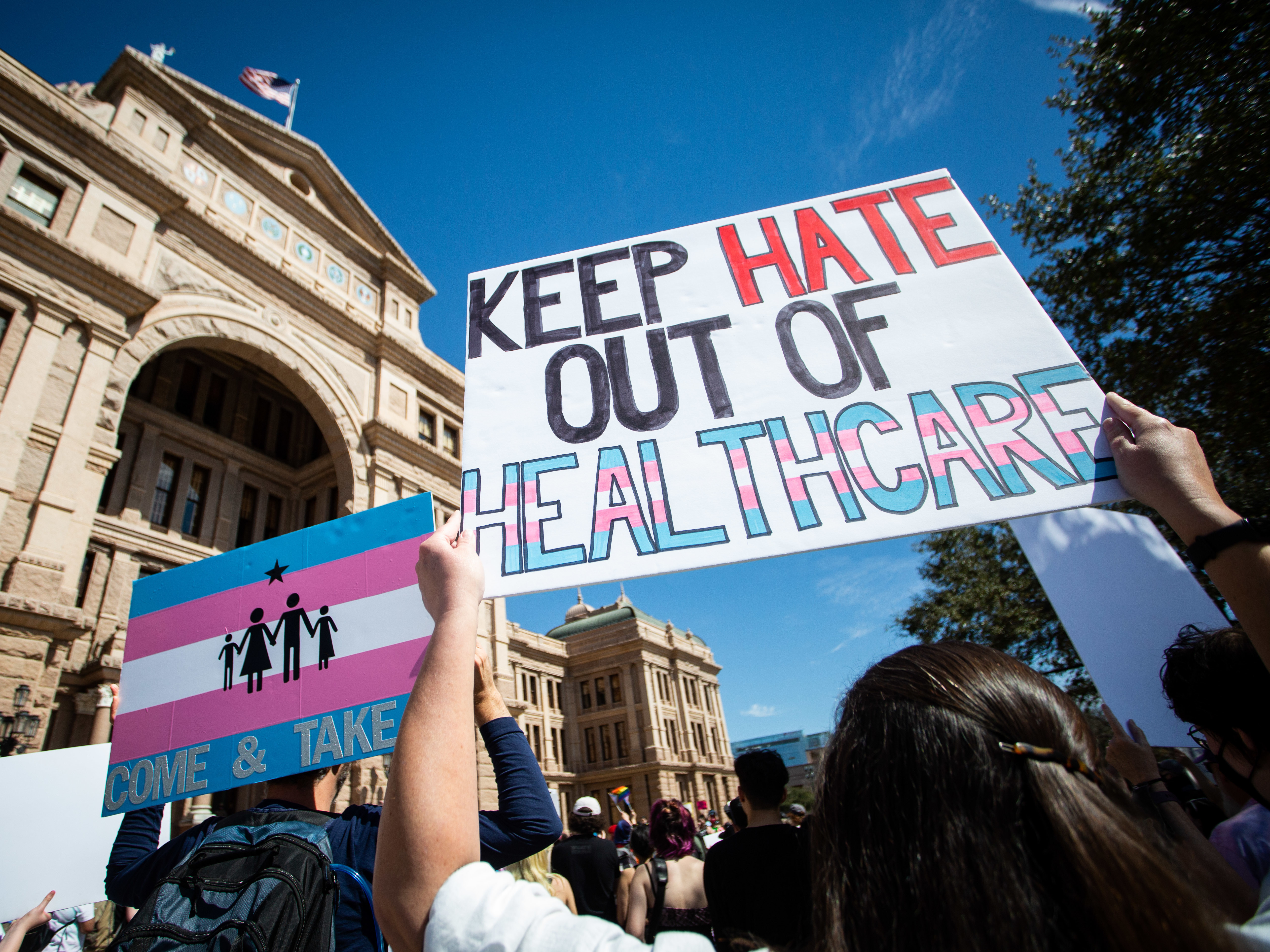 Demonstrators hold signs in support of transgender youth at the Texas State Capitol. (Gabriel C. Pérez/KUT)