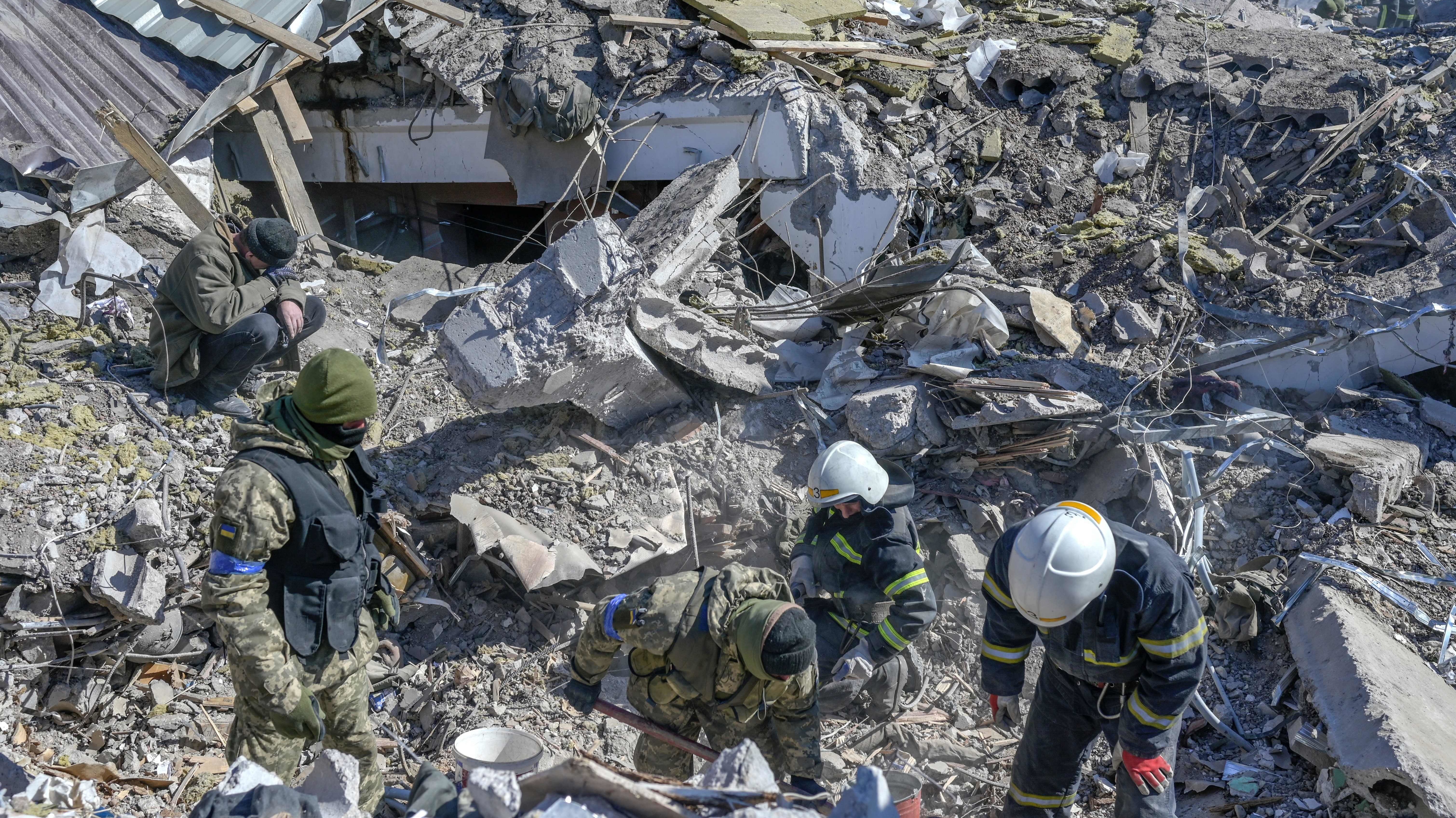 Ukrainian soldiers and rescue officers search for bodies in the debris at a military school in Mykolaiv on Saturday. Russian rockets hit the school the day before.