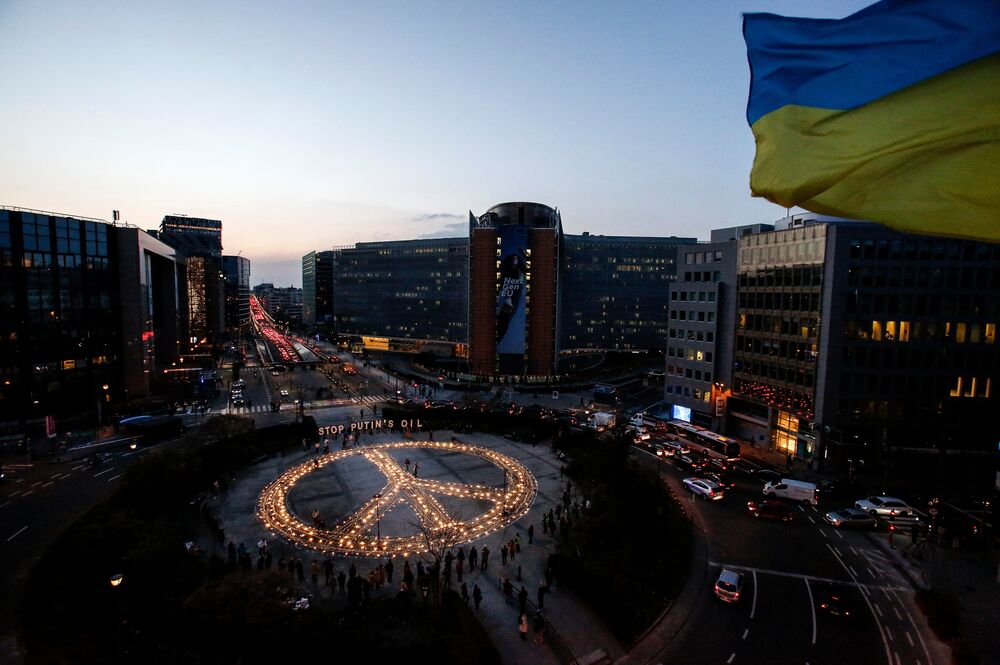 Demonstrators stand around a peace sign during a vigil for Ukraine near the European Union headquarters in Brussels on Tuesday. Activists are calling on EU leaders to impose a full ban on Russian fuel. (AFP via Getty Images)