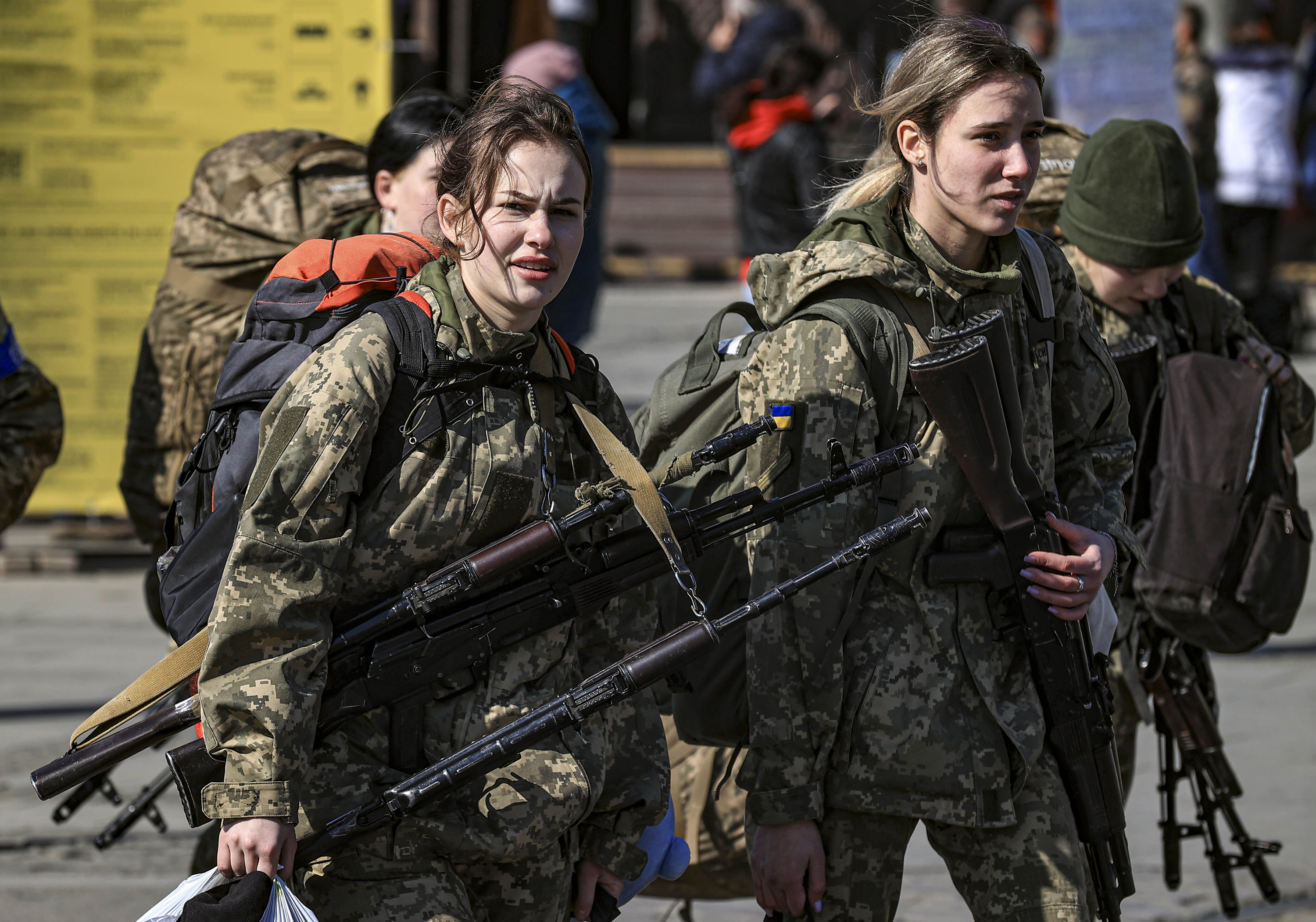 March 24: Ukrainian soldiers head to the front line as displaced civilians swarm a train station in Lviv to flee Russian attacks.