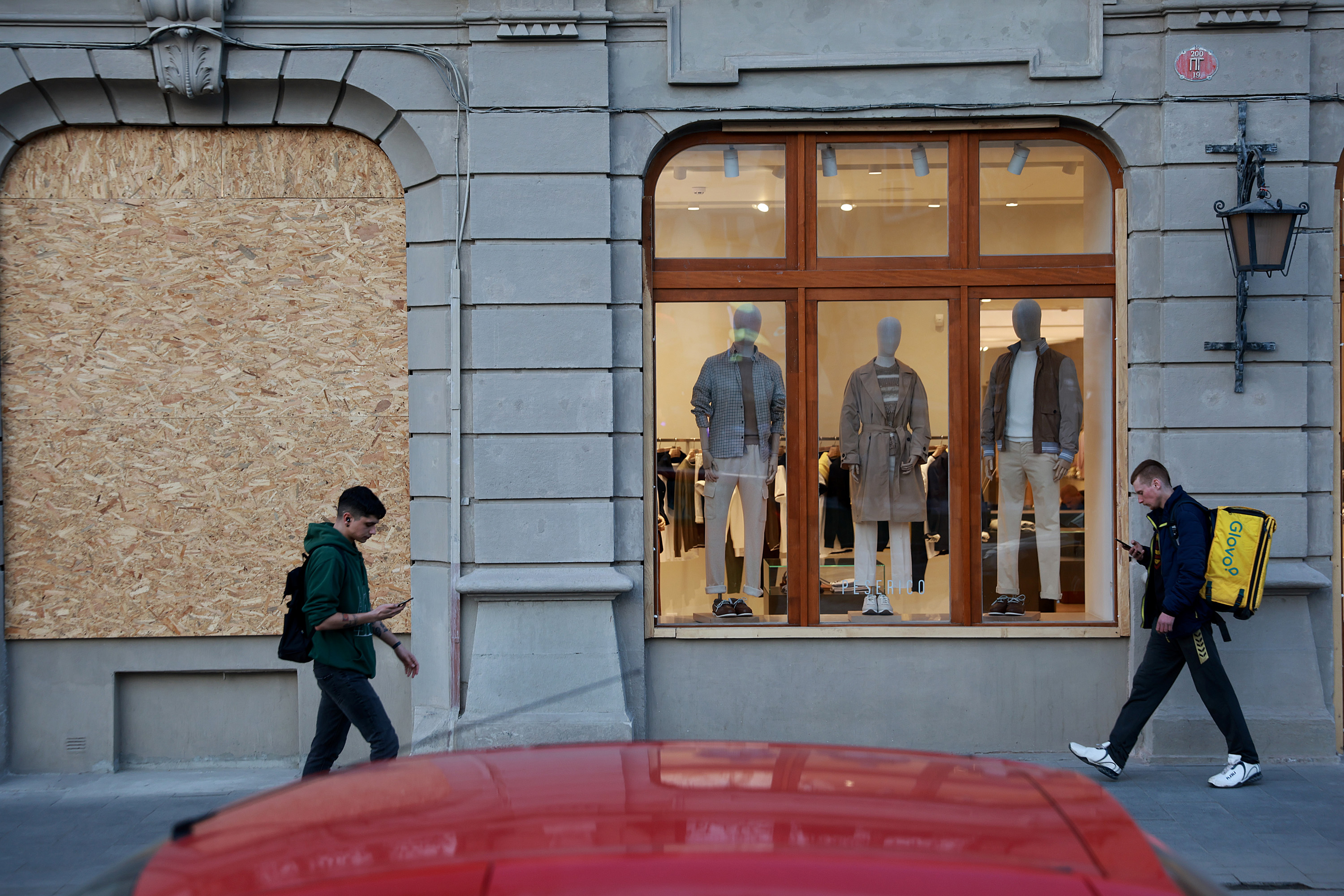 March 23: People walk past a boarded up window as they make their way through a street as the city continues to prepare for the possibility of a Russian military attack in Lviv.