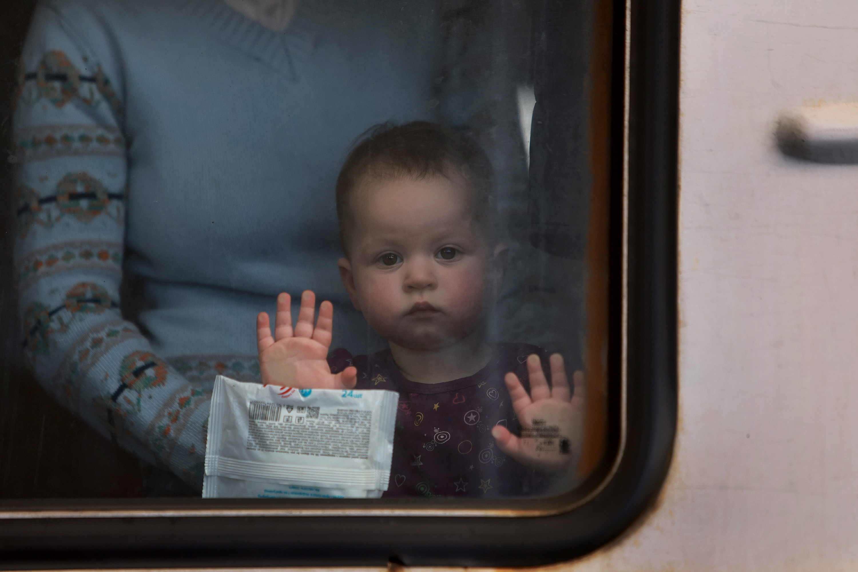 March 23: A child looks out a window as people fleeing Russian attacks on their hometowns leave Lviv on a train for Poland.