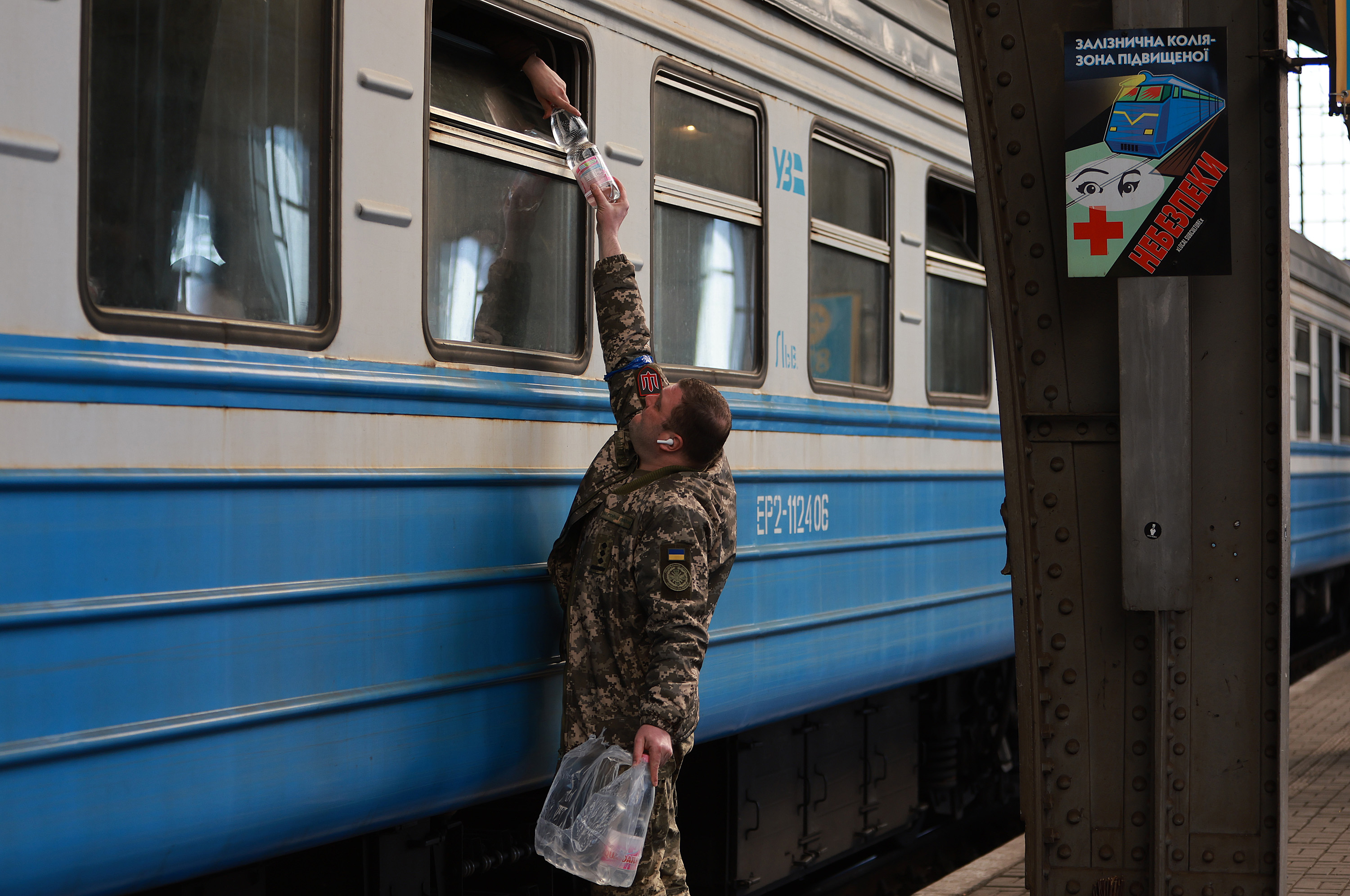 March 23: A soldier hands water to people in Lviv leaving on a train for Poland as they flee their hometowns.