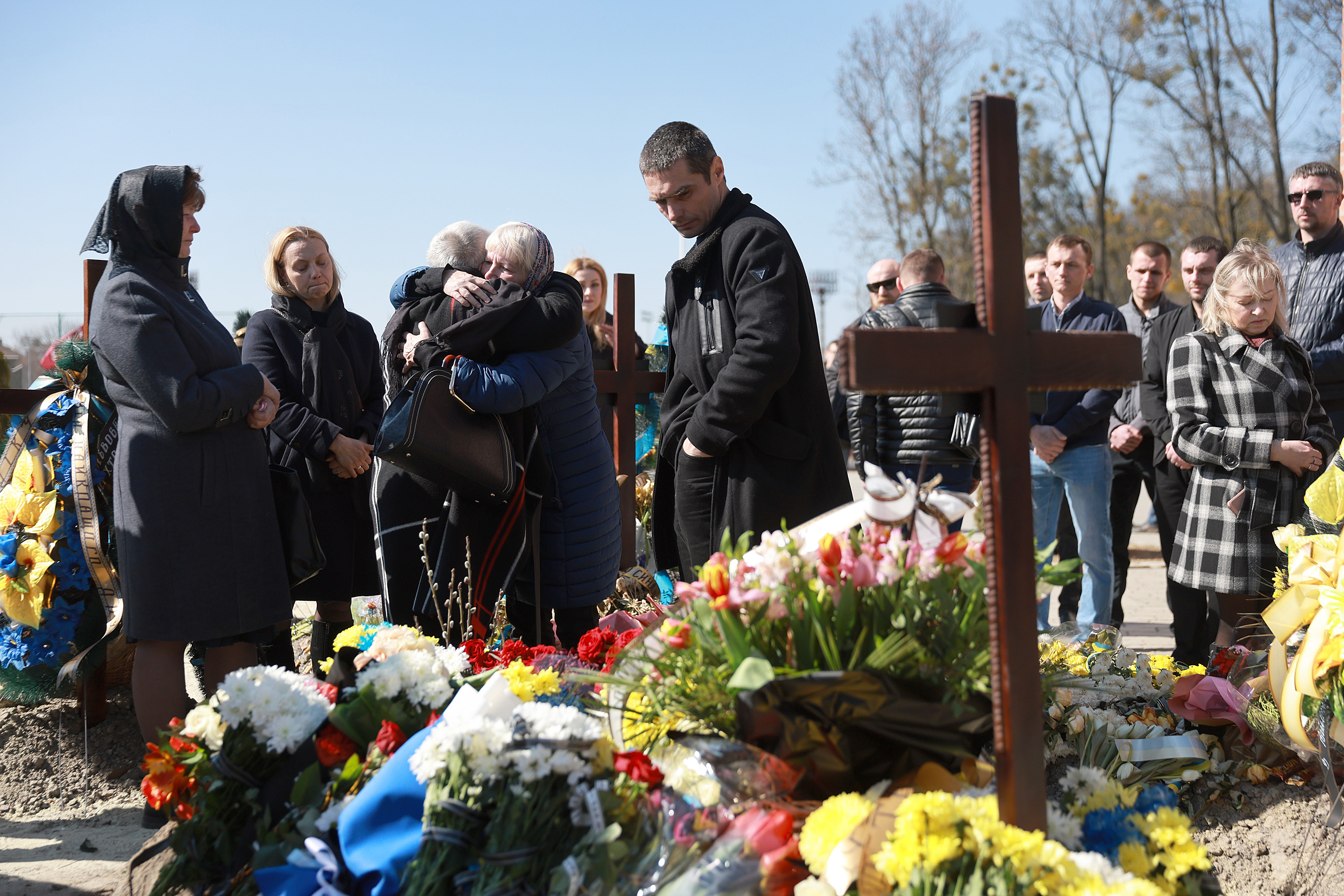 March 24: Yuri Vododymyrovych, center, stands next to the burial site of his twin brother, Fedorchyk Ihor Vododymyrovych, during his burial in Lviv. Vododymyrovych was a member of the Ukrainian Army and died fighting the Russians in the city of Nova Kakhovka.