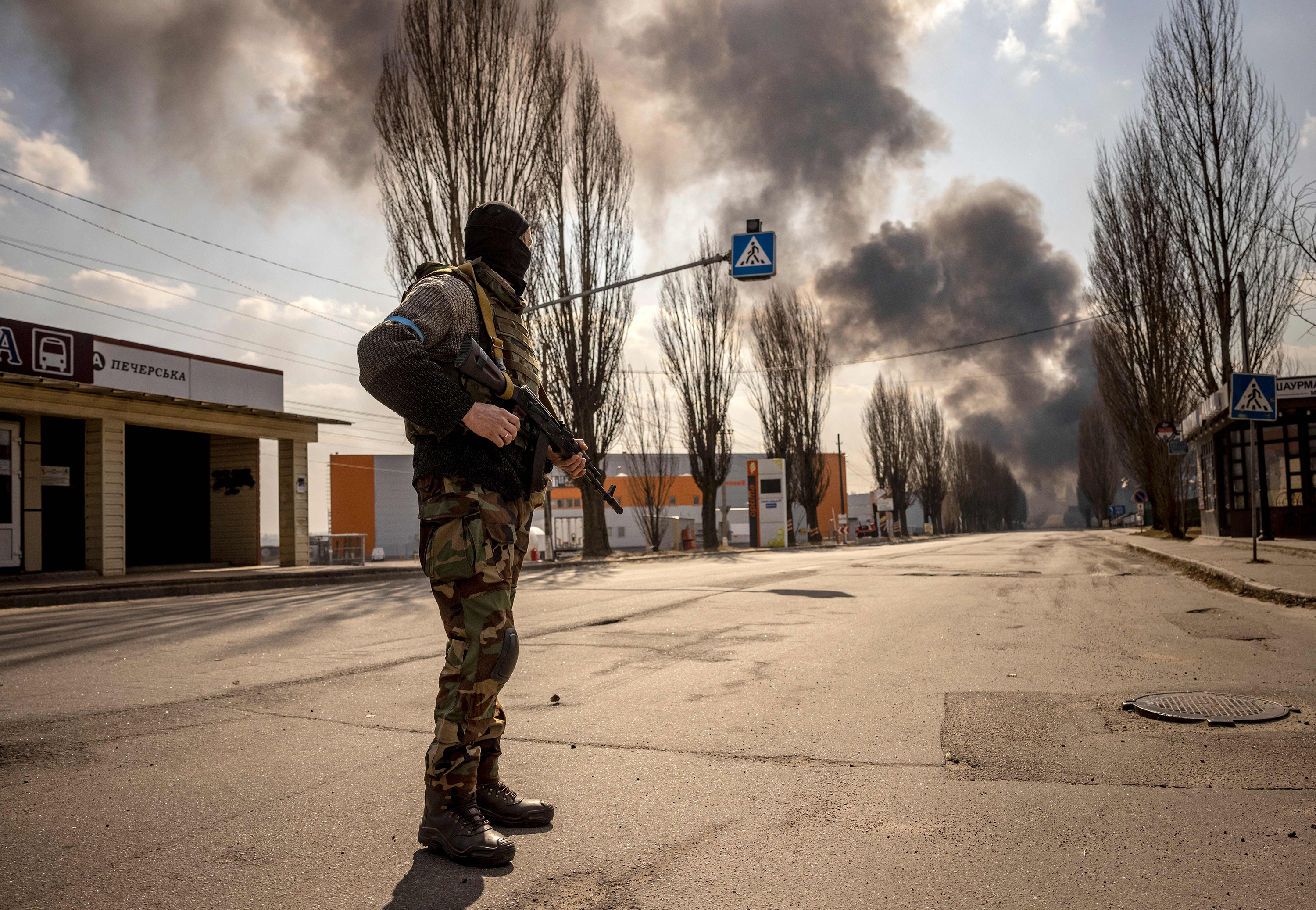 March 24: A Ukrainien serviceman stands guard near a burning warehouse hit by a Russian shell in the suburbs of the capital Kyiv.