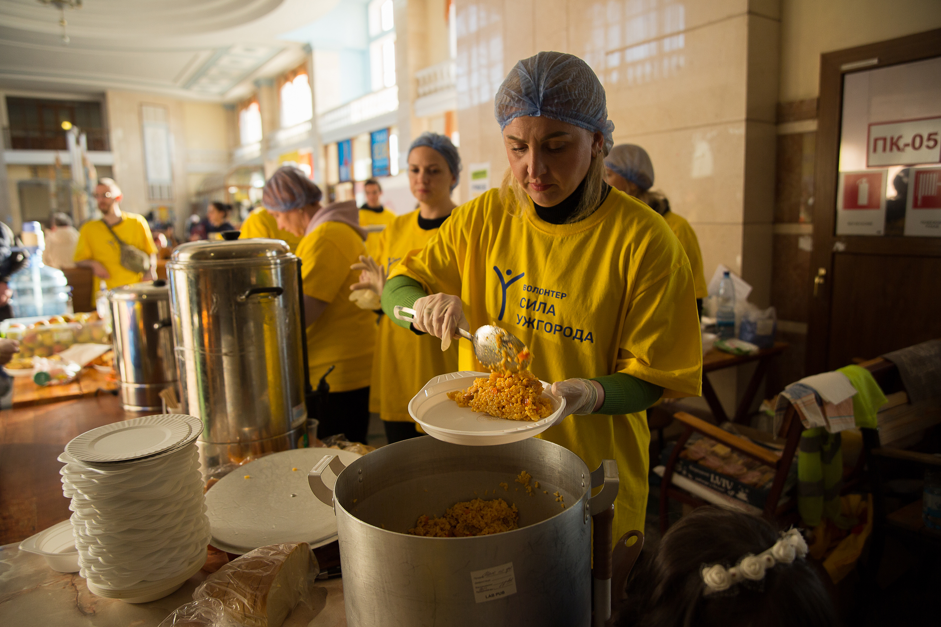 March 24: A volunteer from the initiative 'Sila Uzhhoroda' (The Power of Uzhhorod) serves meals to fleeing refugees at Uzhhorod train station in Uzhhorod, Ukraine. Sila Uzhhoroda is the only organization serving cooked food to refugees at the train station. Currently, initiative Sila Uzhhoroda serves between 6000 - 7000 meals per day.